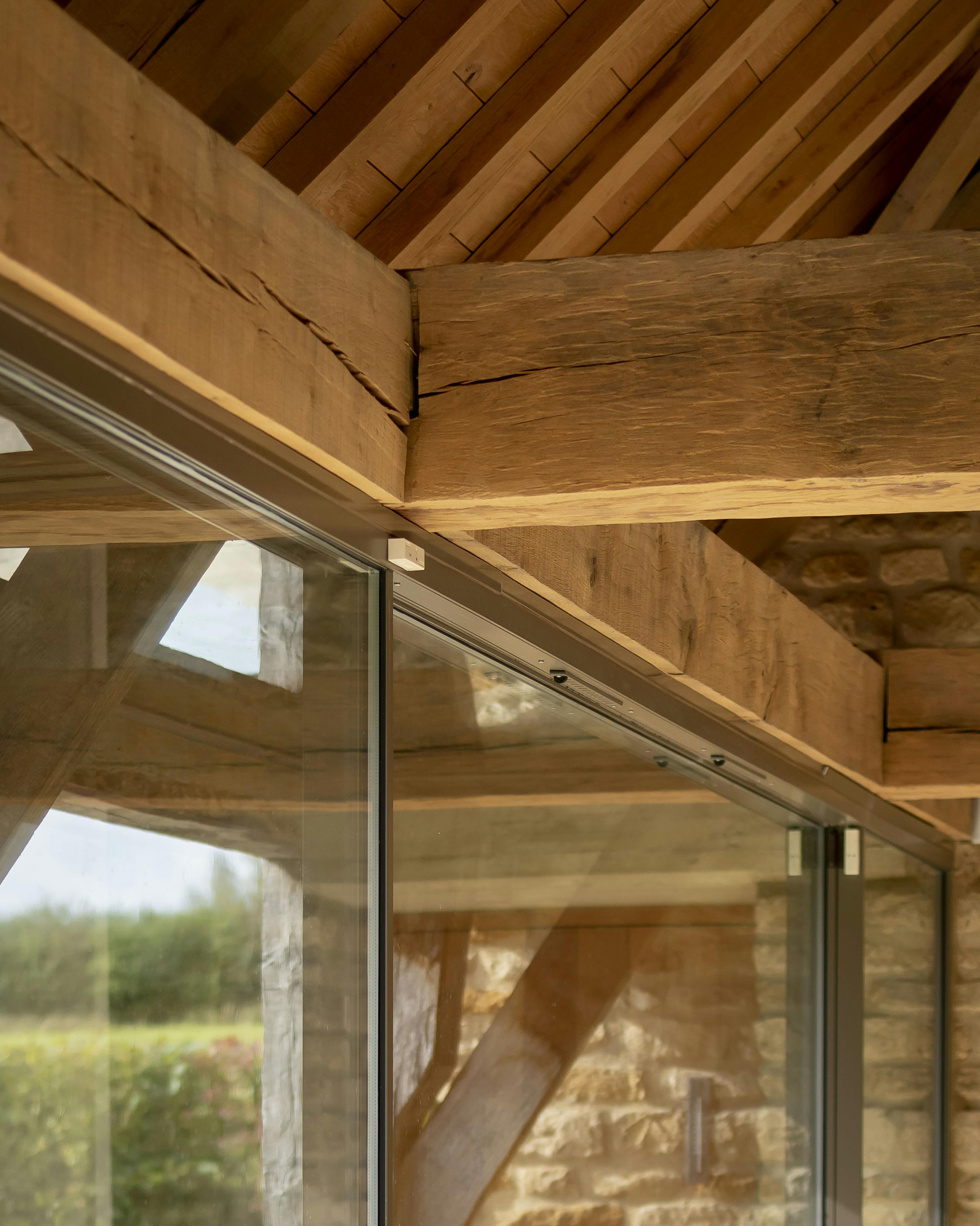 Close-up of oak beams and joinery, with a view of a large expanse of glazed panels
