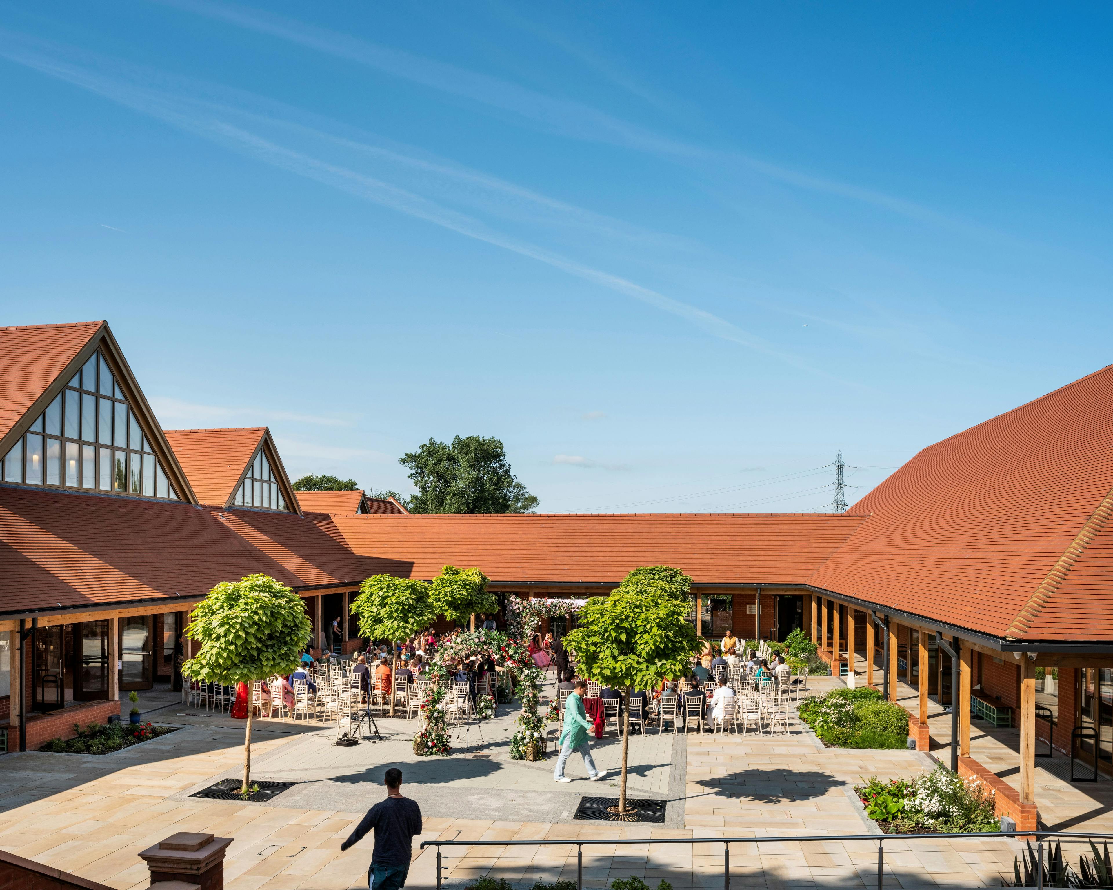 A gathering of people inside a courtyard of a Hindu Temple with green oak framed veranda