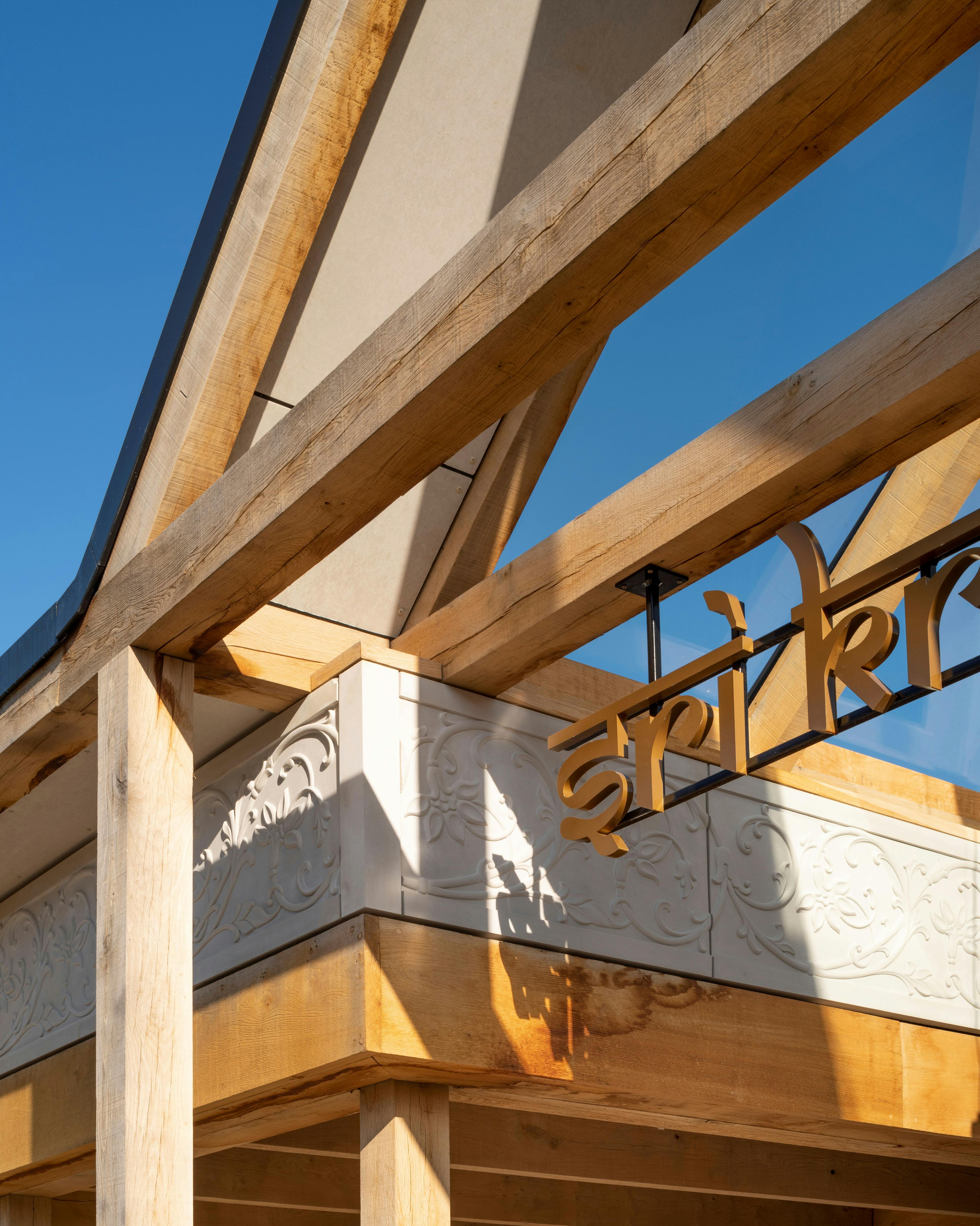 A close up detailed image of a green oak framed entranceway of a Hindu Temple
