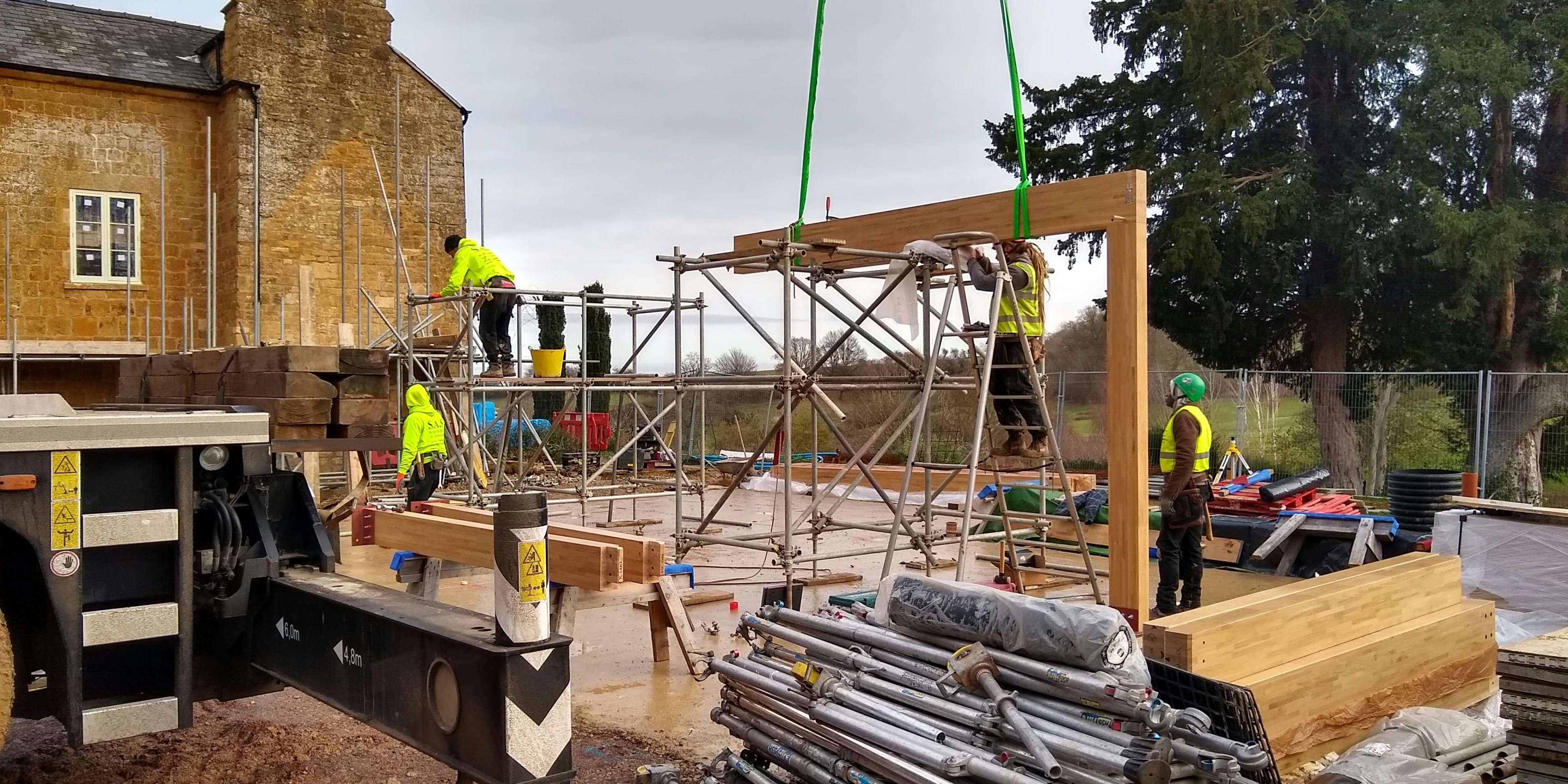 On-site construction showing assembly of a glulam timber frame for a building extension