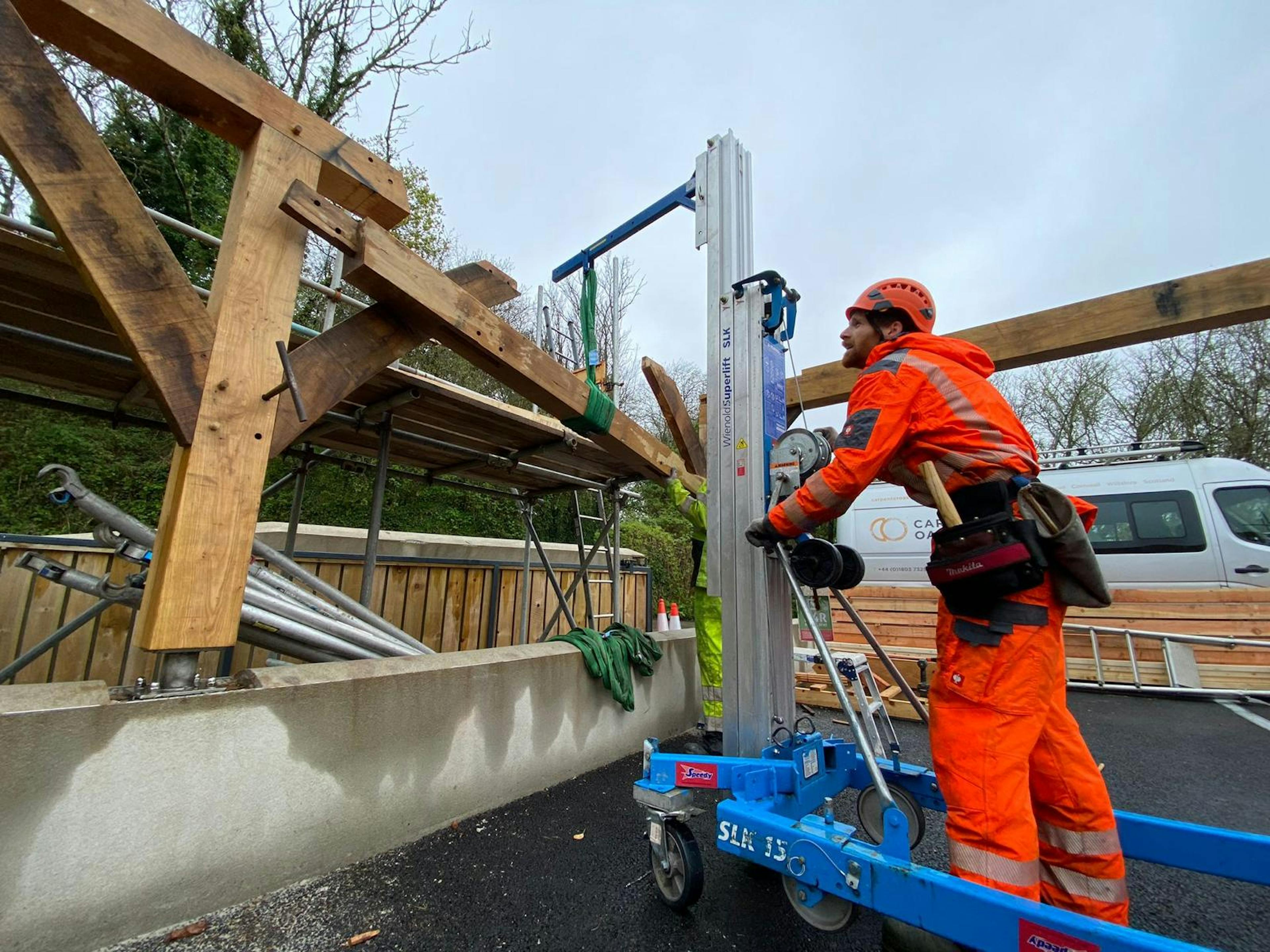 On-site carpenter assisting with a crane lift of timber components