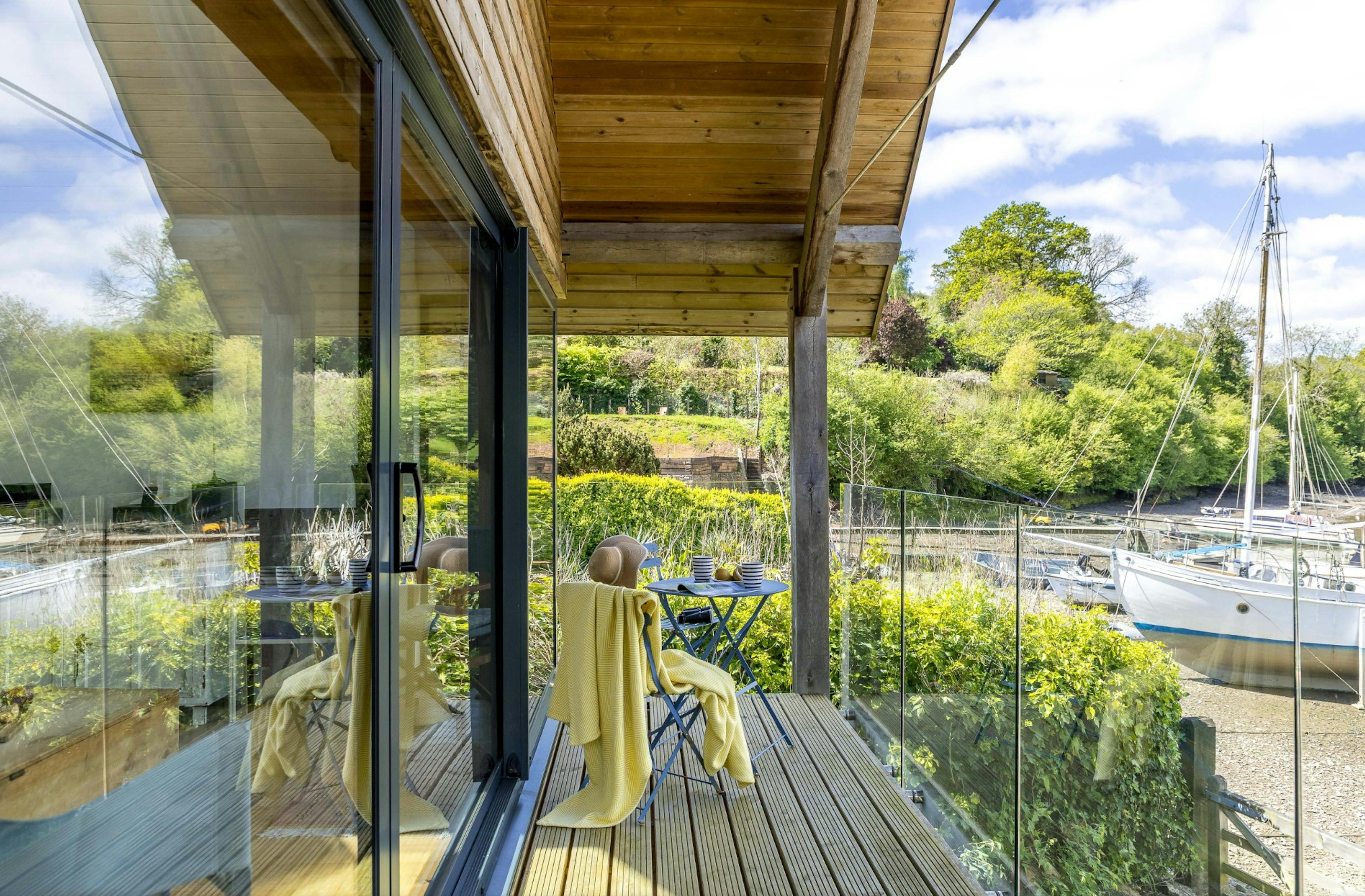 The balcony of an oak framed boathouse on the edge of a river