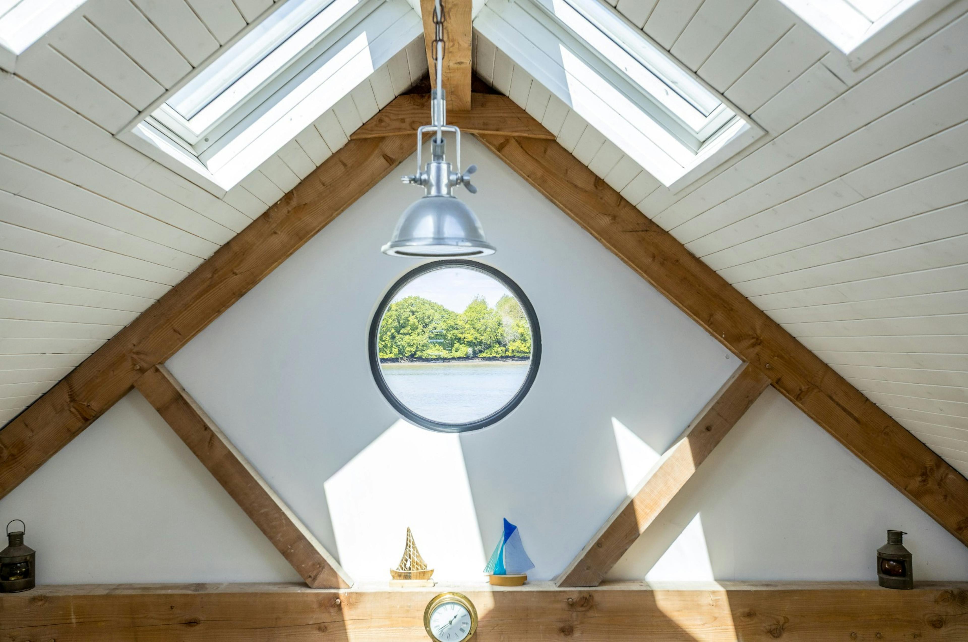 The ceiling of an oak framed boathouse with a round porthole window