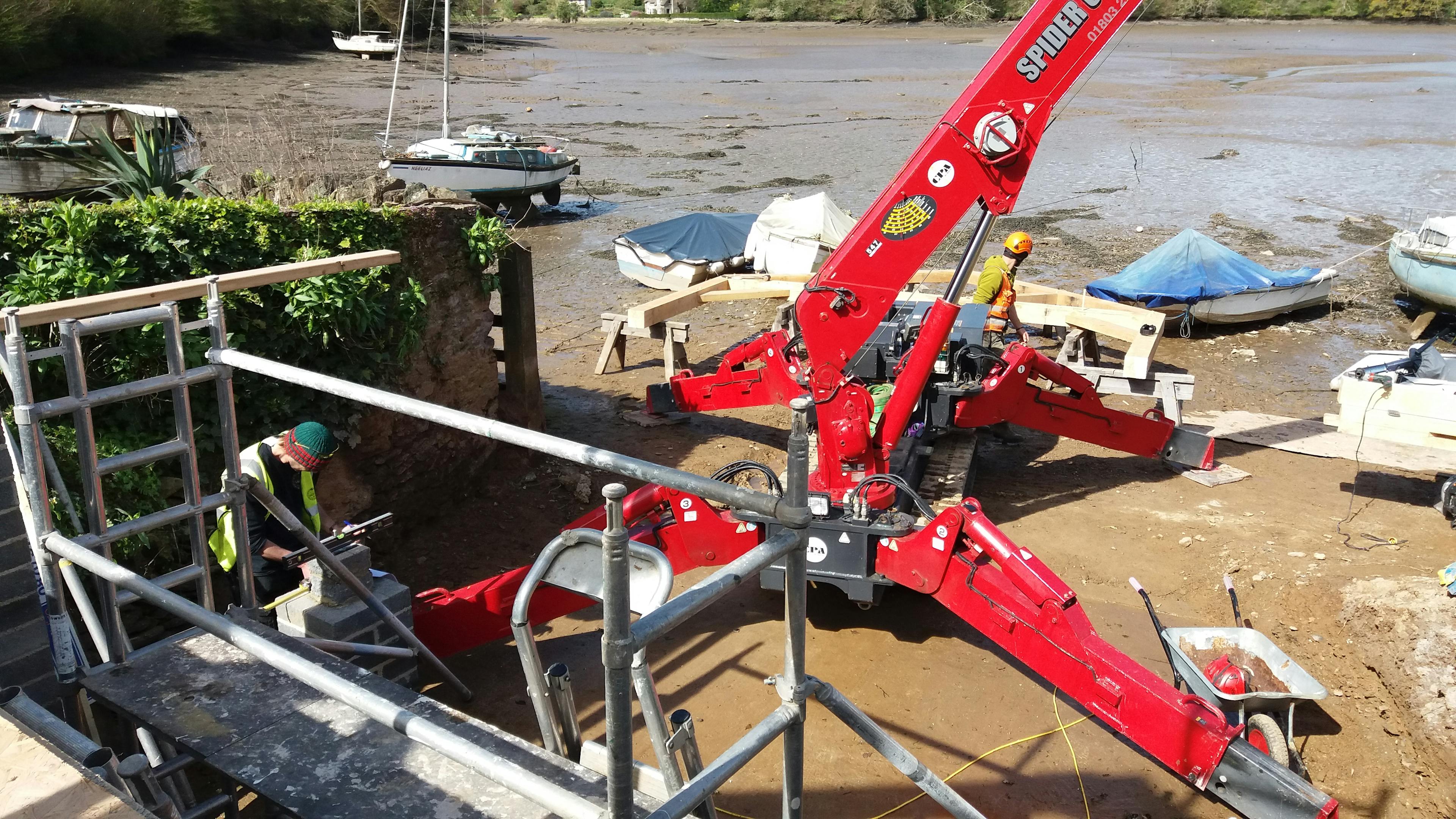 A red spider crane on a riverbed whilst the tide is out