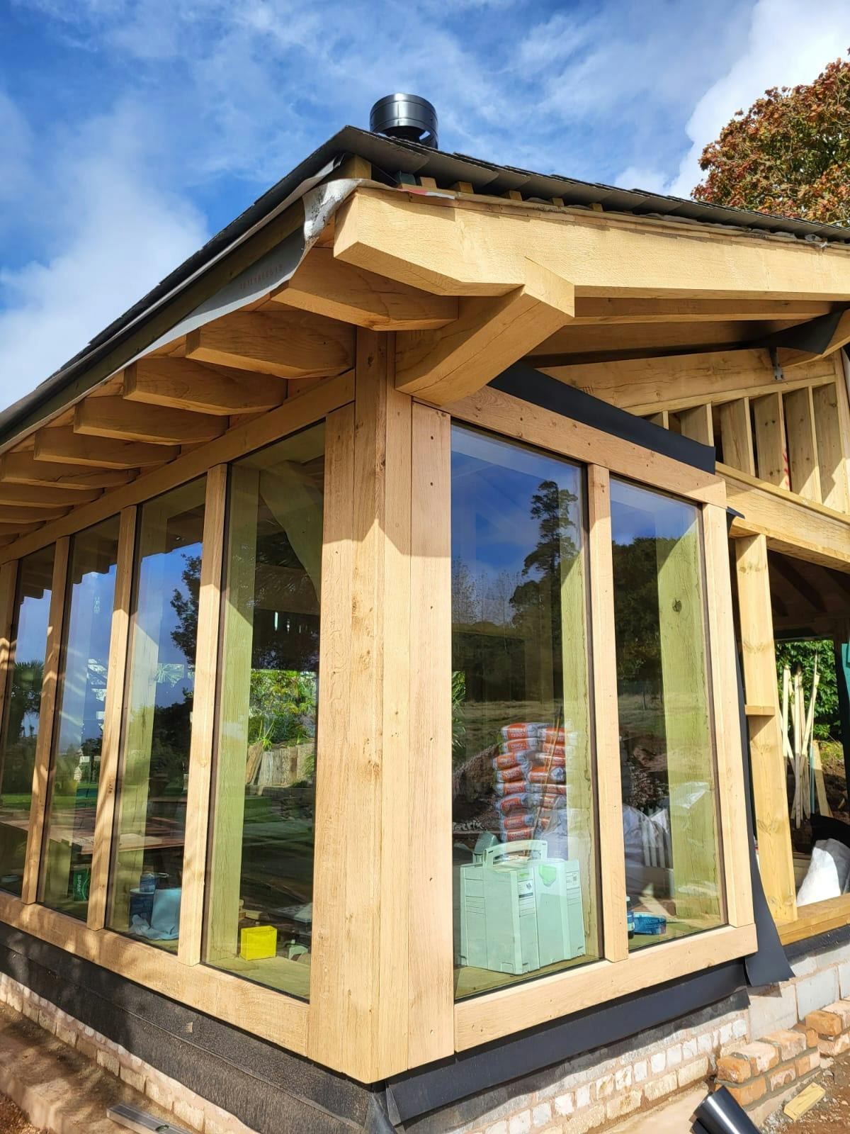 The glazing of a pool building annexe with an oak frame during construction