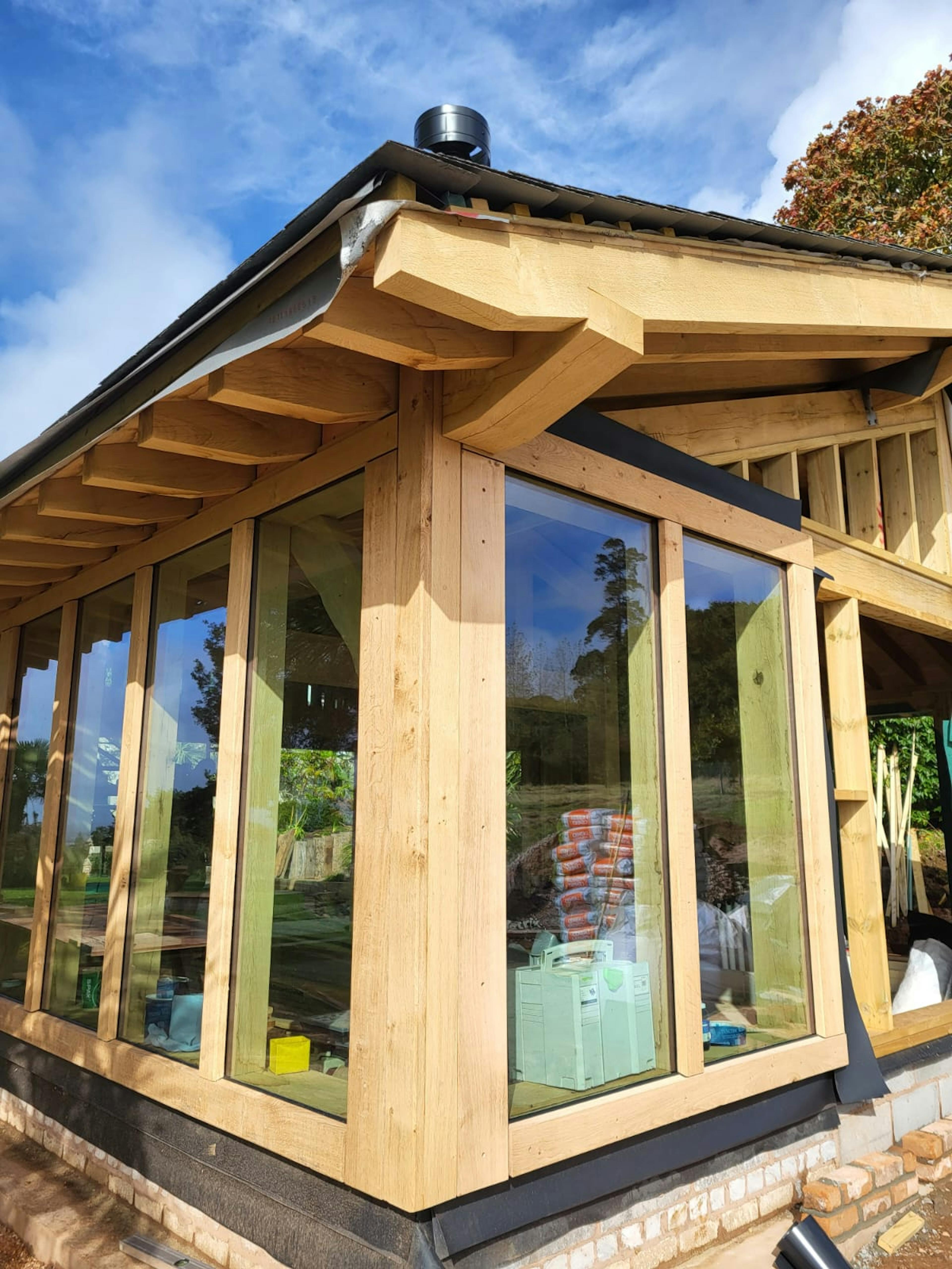 The glazing of a pool building annexe with an oak frame during construction