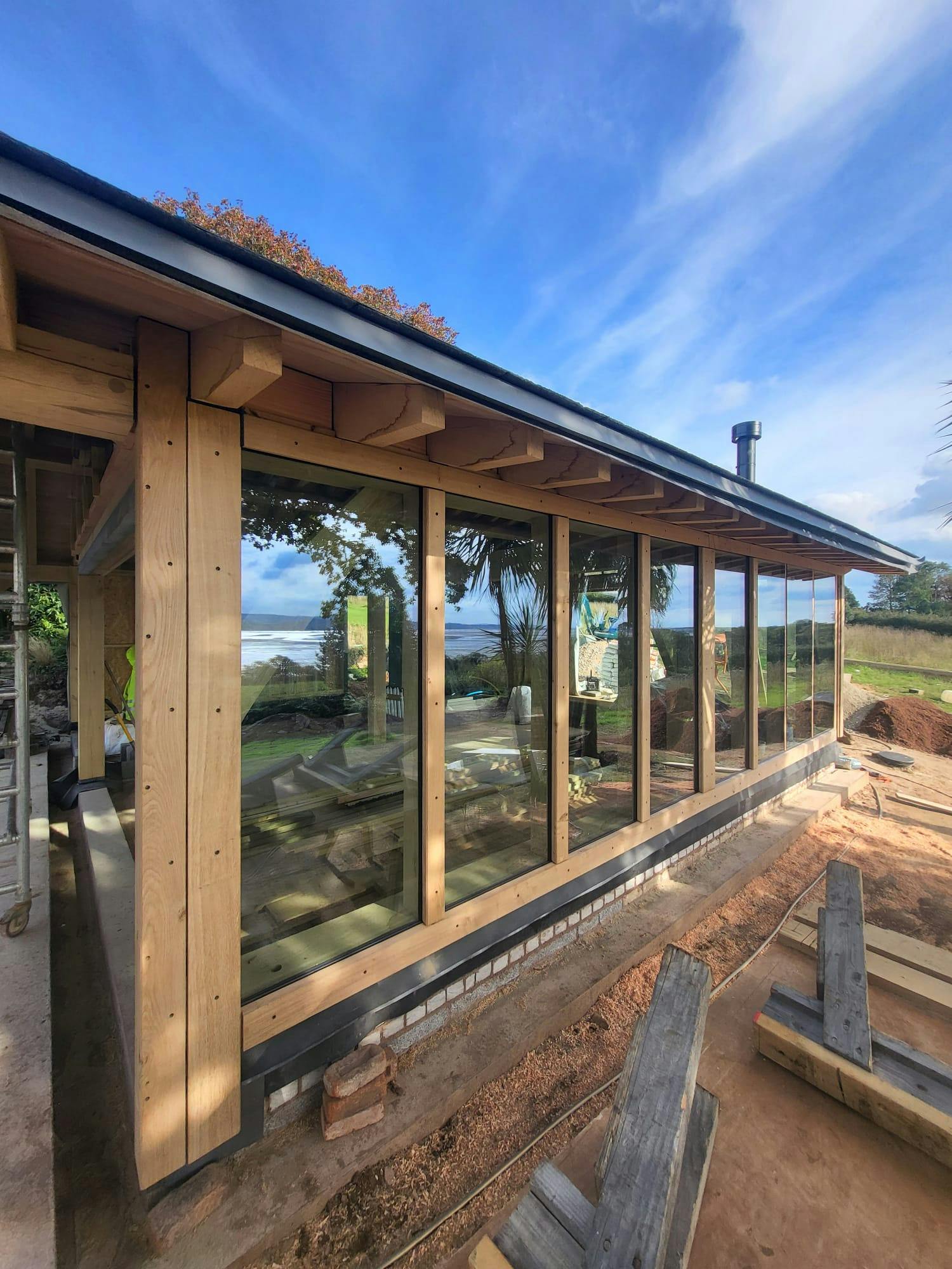 The glazing of a pool building annexe with an oak frame during construction