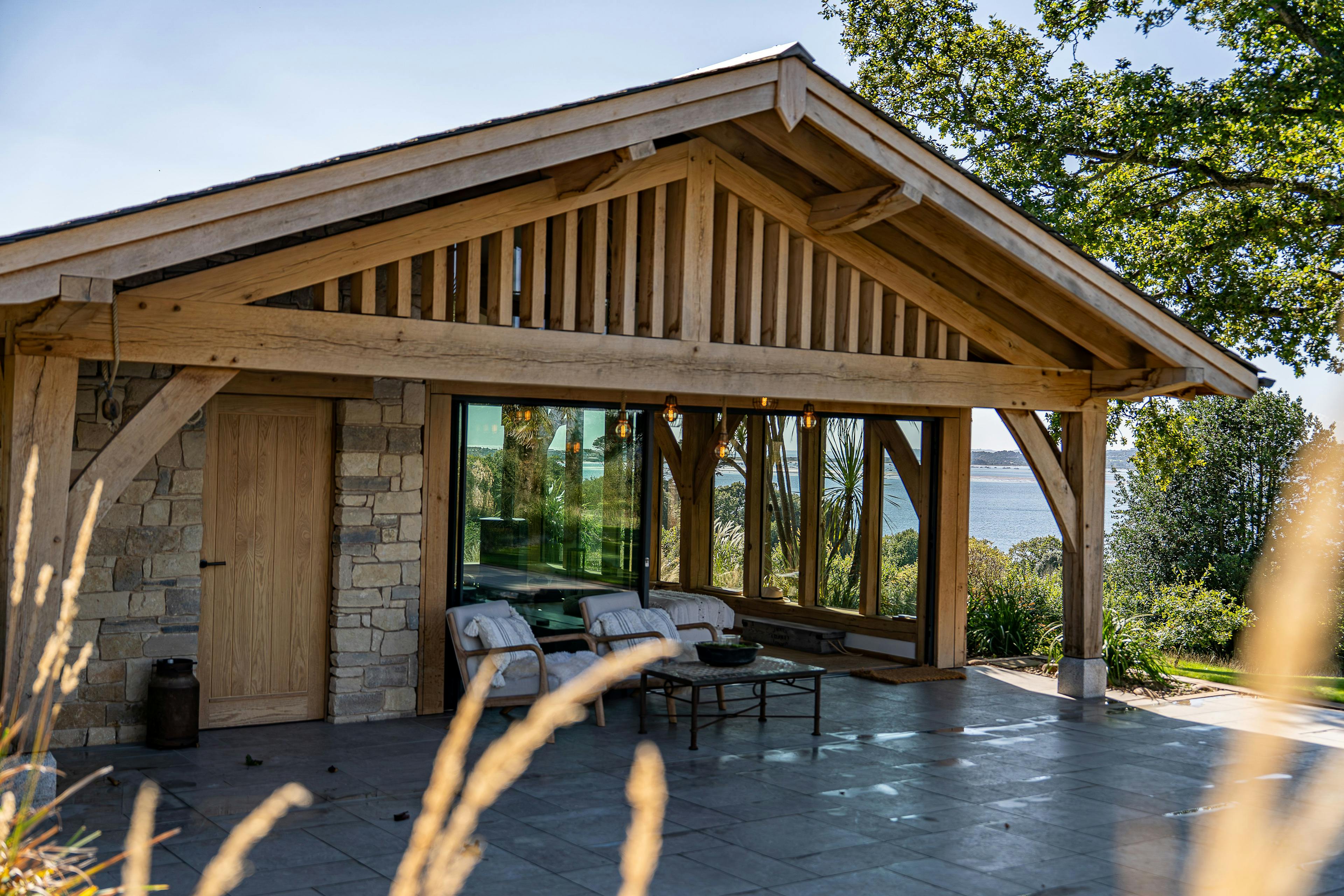 An oak framed pool building annexe with a low pitch roof and brise soleil
