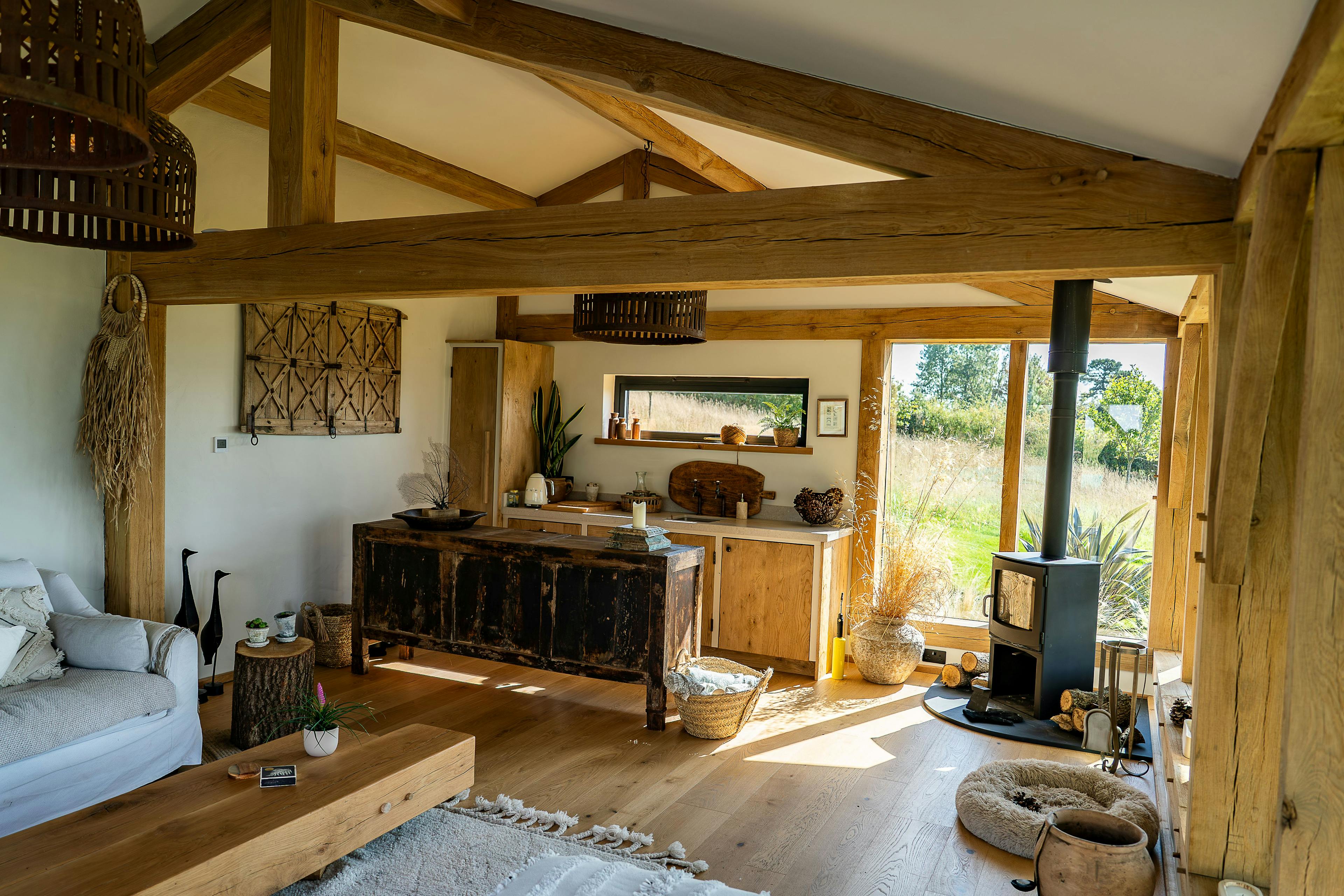 Inside an oak framed pool building annexe with a kitchen, comfortable sitting area and log burner