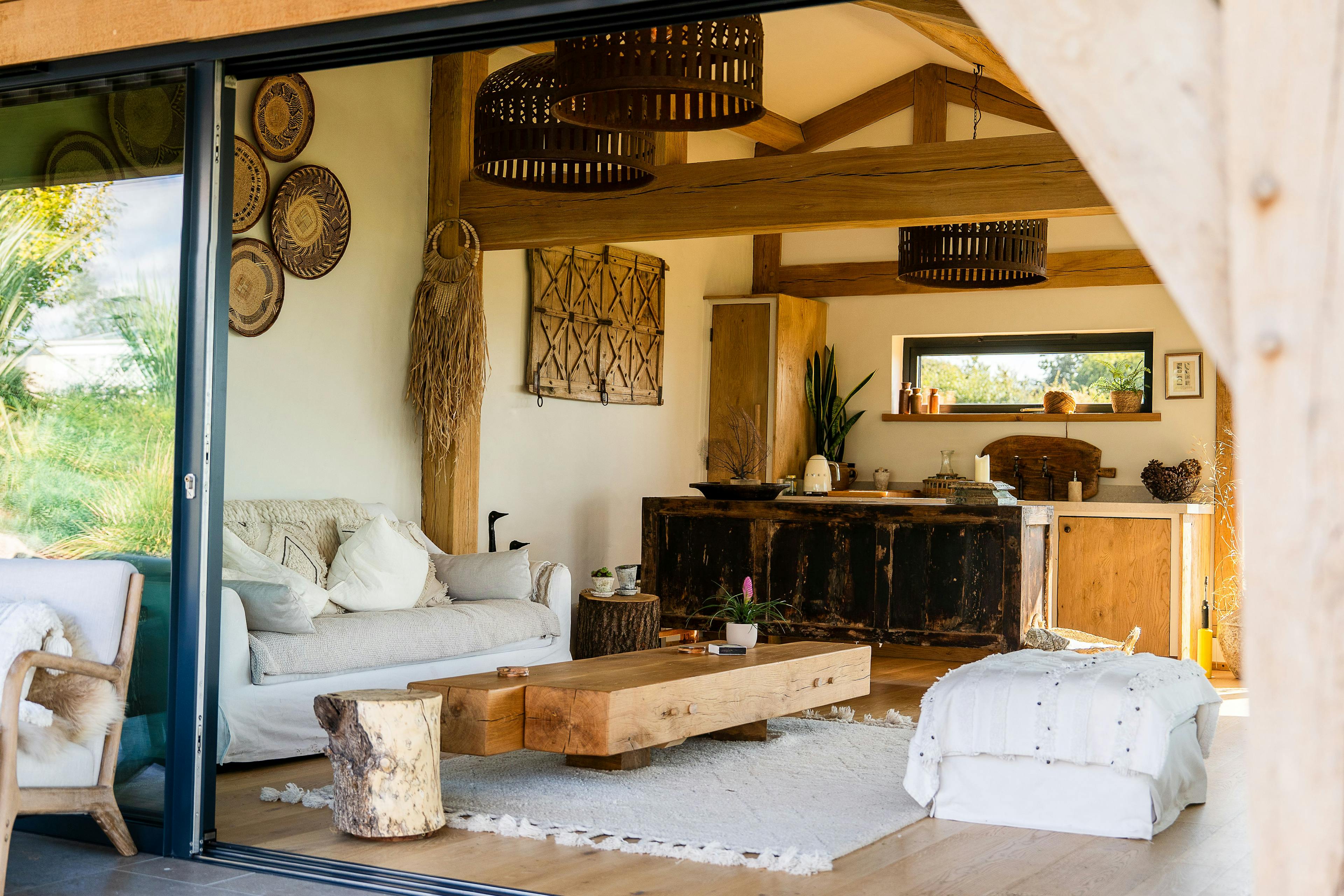 Inside an oak framed pool building annexe with a kitchen, comfortable sitting area and sliding doors out to a patio