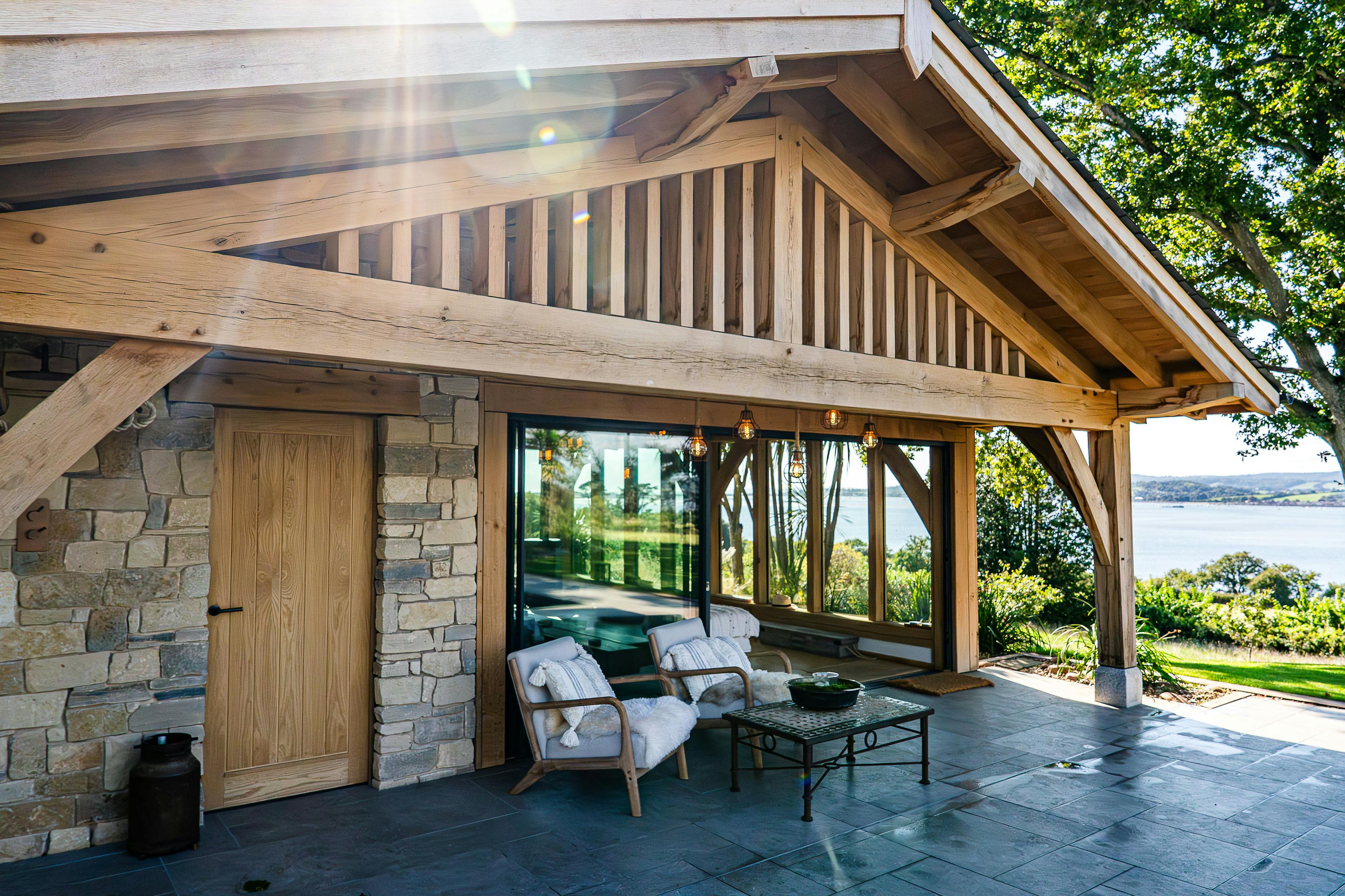 An oak framed pool building annexe with sliding doors out to a patio with seating