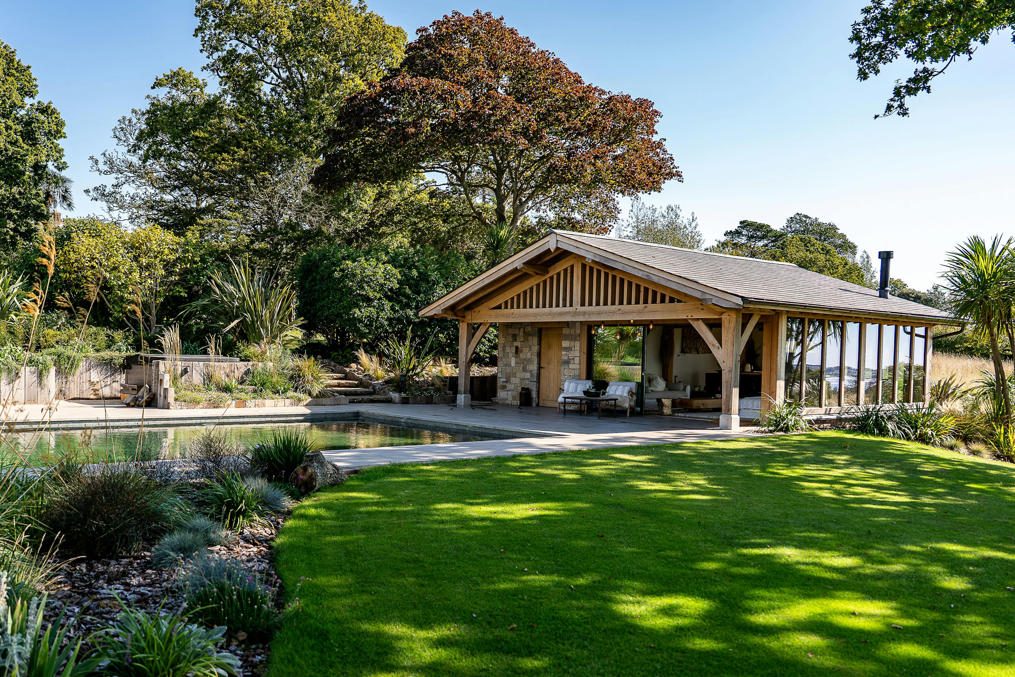 A pool building annexe with an oak frame, low pitch roof and brise soleil in a large garden