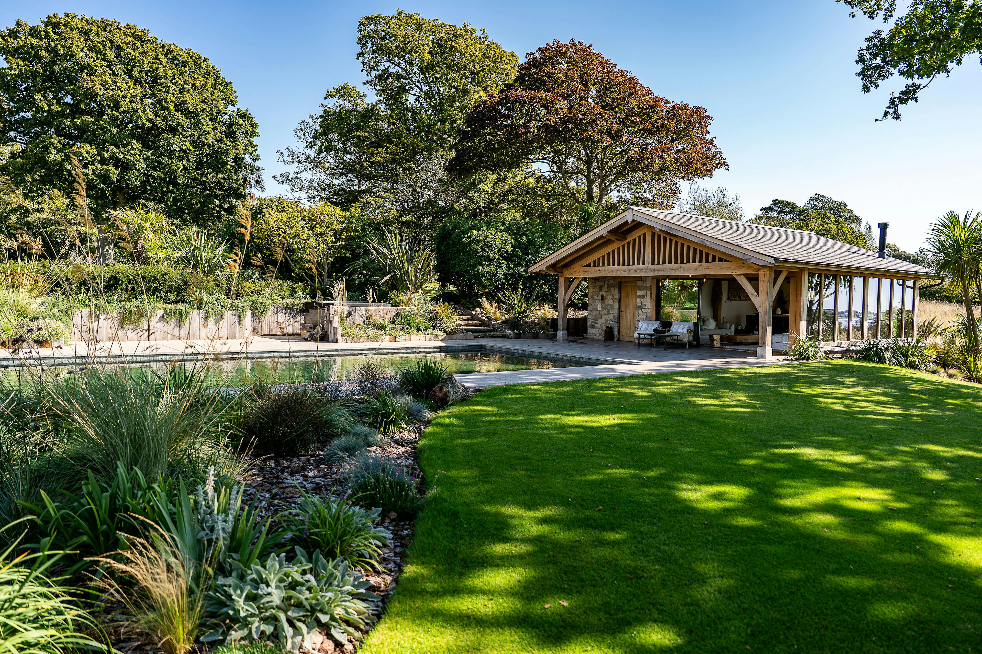 A pool building annexe with an oak frame, low pitch roof and brise soleil in a large garden