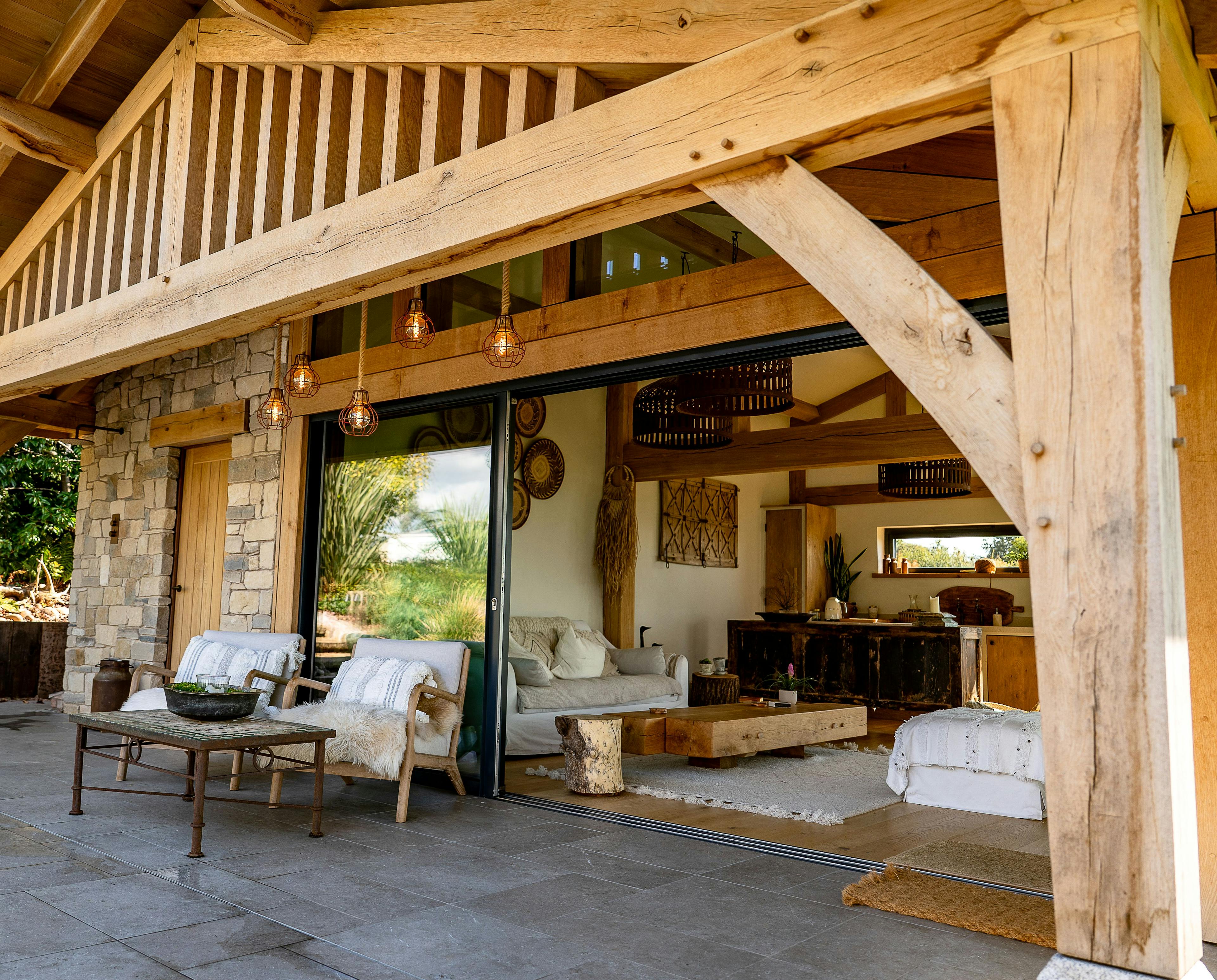 An oak framed pool building annexe with sliding doors out to a patio with seating