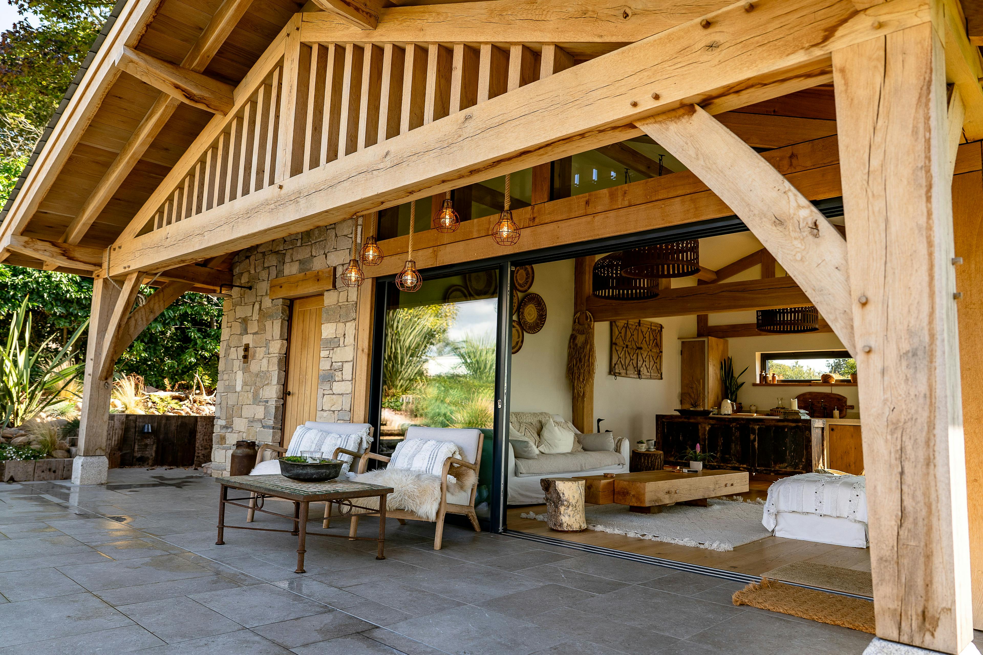 An oak framed pool building annexe with sliding doors out to a patio with seating
