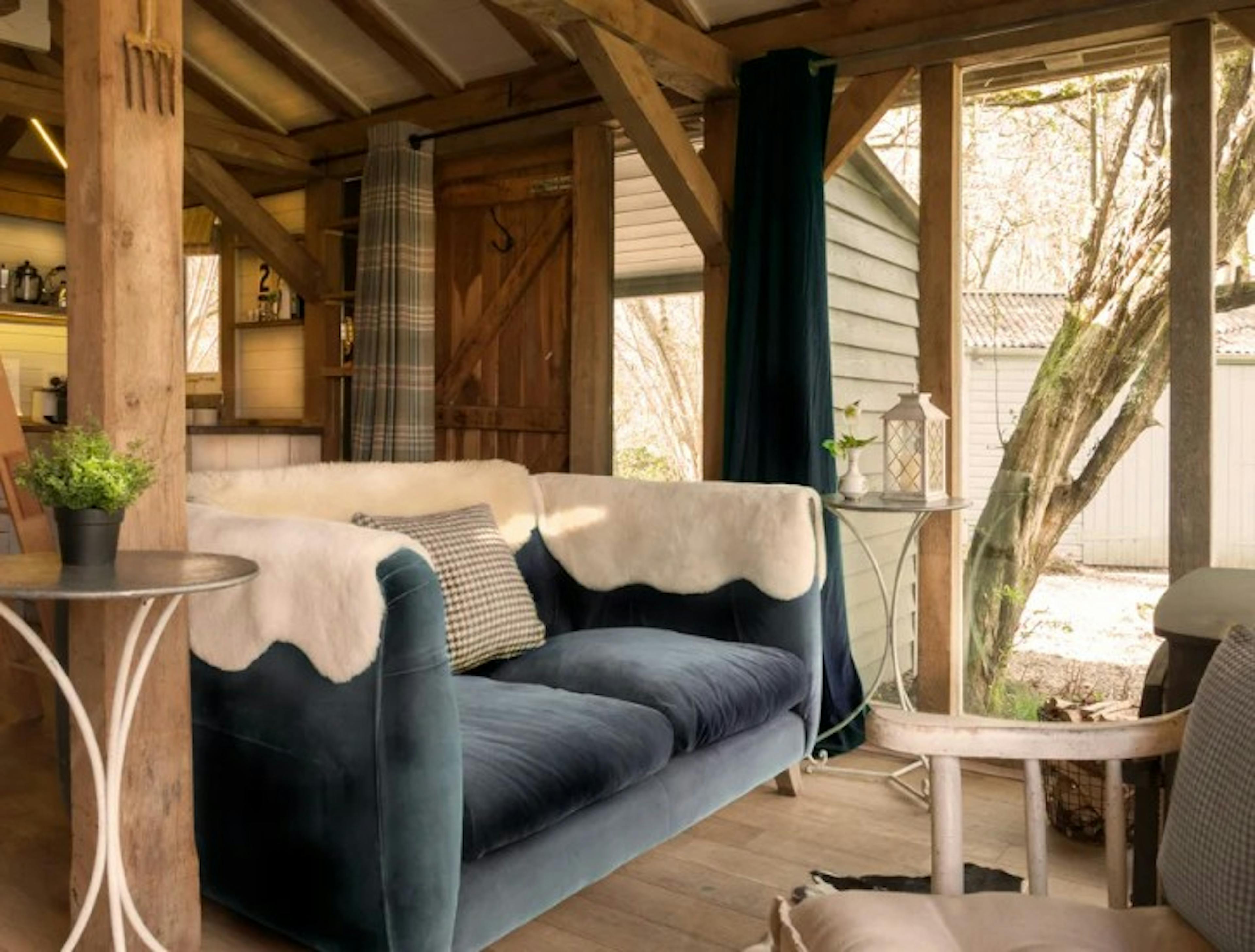 An open plan oak framed cabin with dining, bedroom areas and log burner