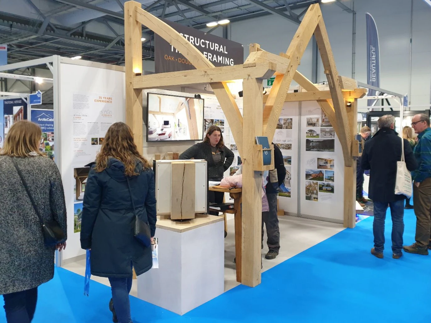 Staff and customers at an oak frame stand at a trade show event for self-builders.
