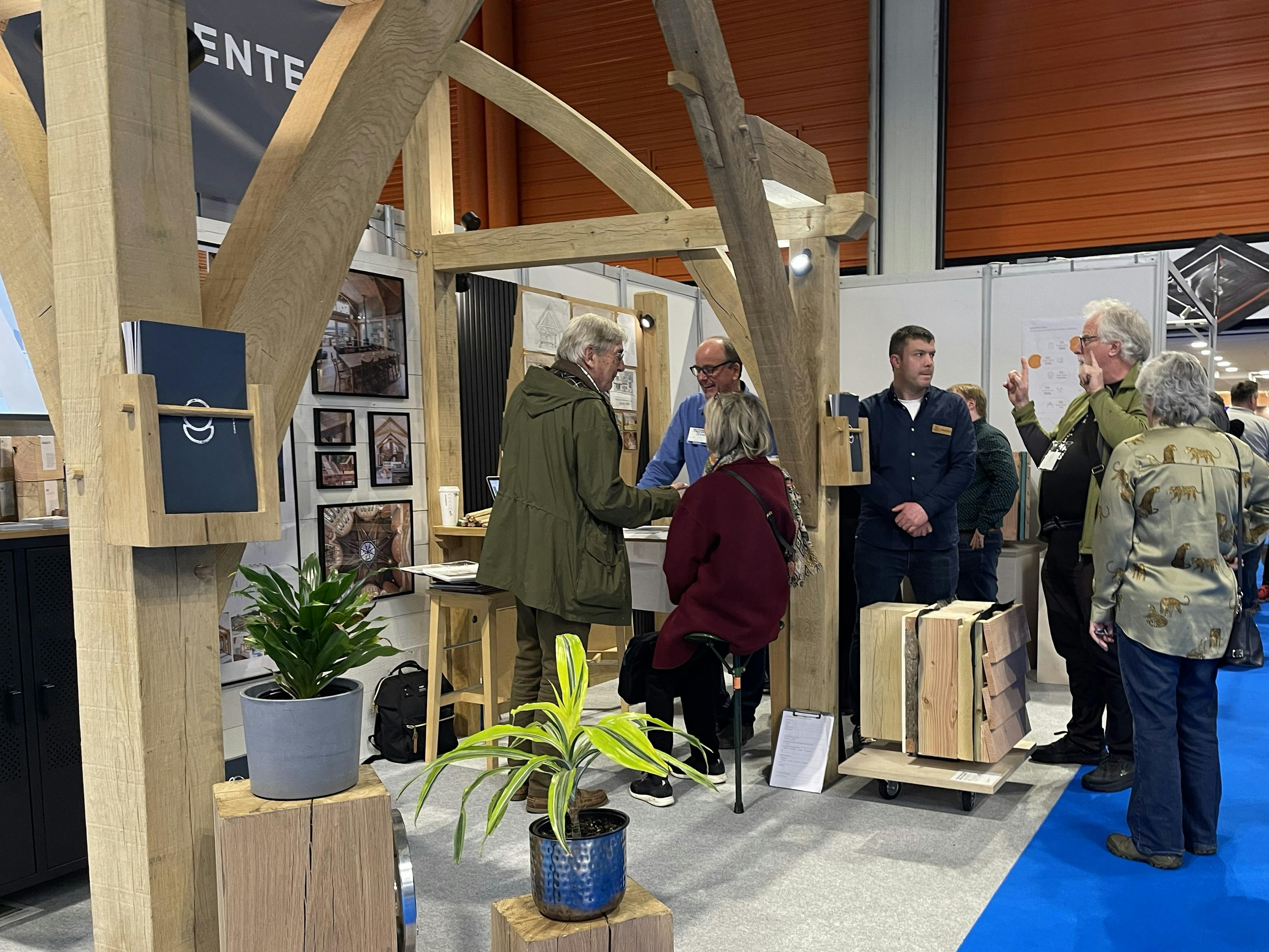 Staff and customers at an oak frame stand at a trade show event for self-builders.