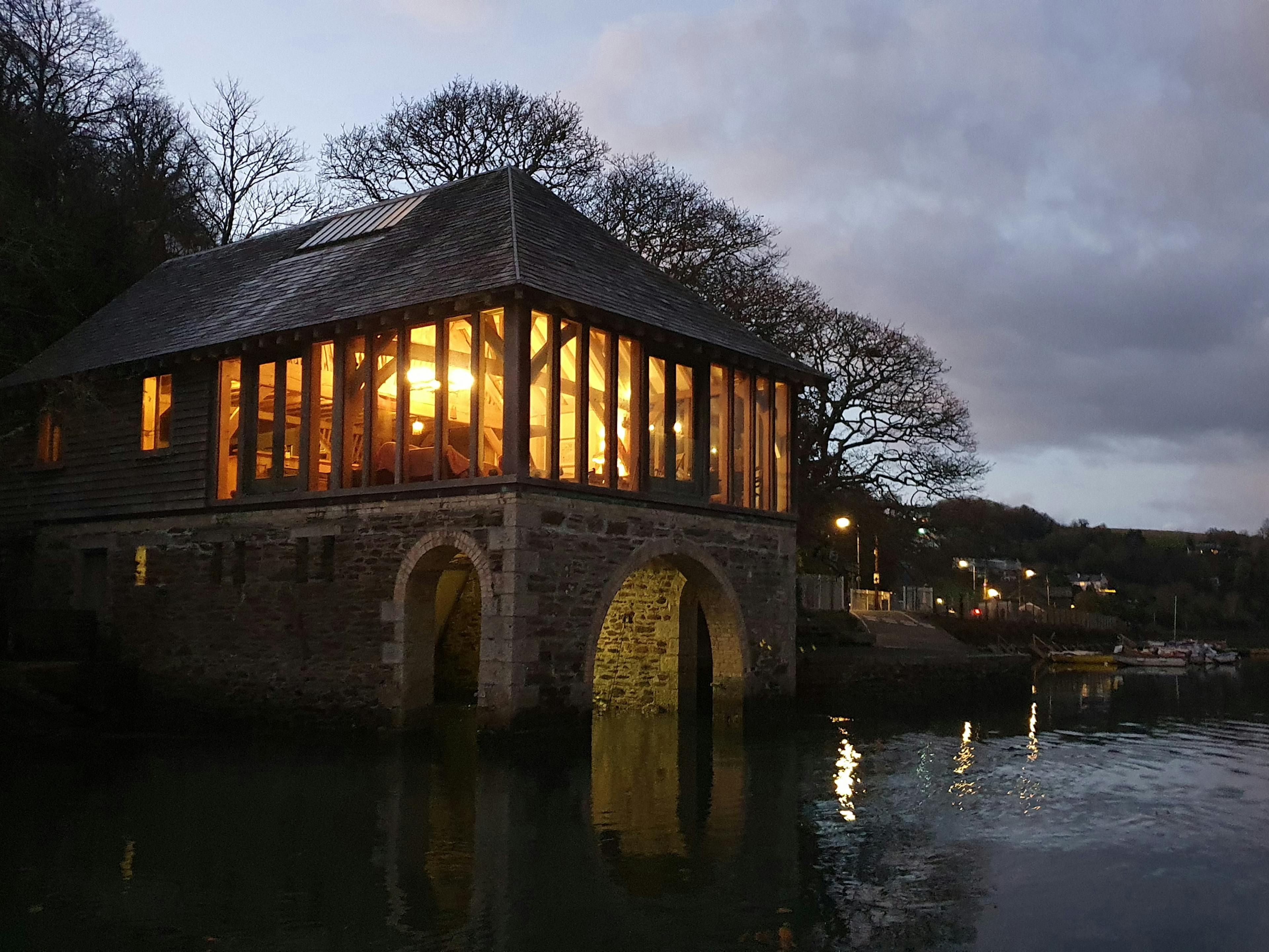 At dusk an oak framed retreat on top of a stone boathouse on the River Fowey 