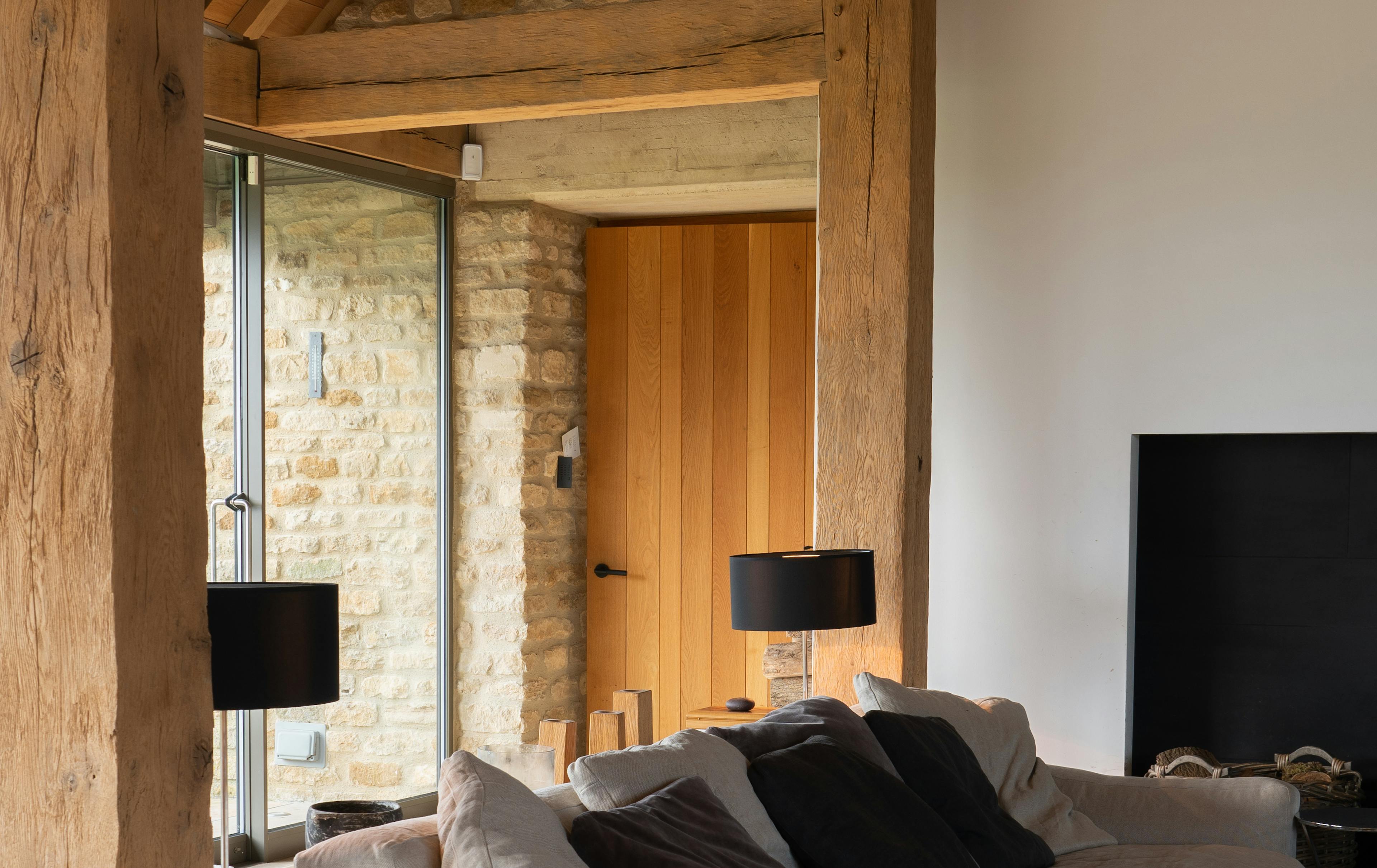 Interior of a spacious renovated oak-framed barn featuring exposed rustic beams, and a contemporary lounge area