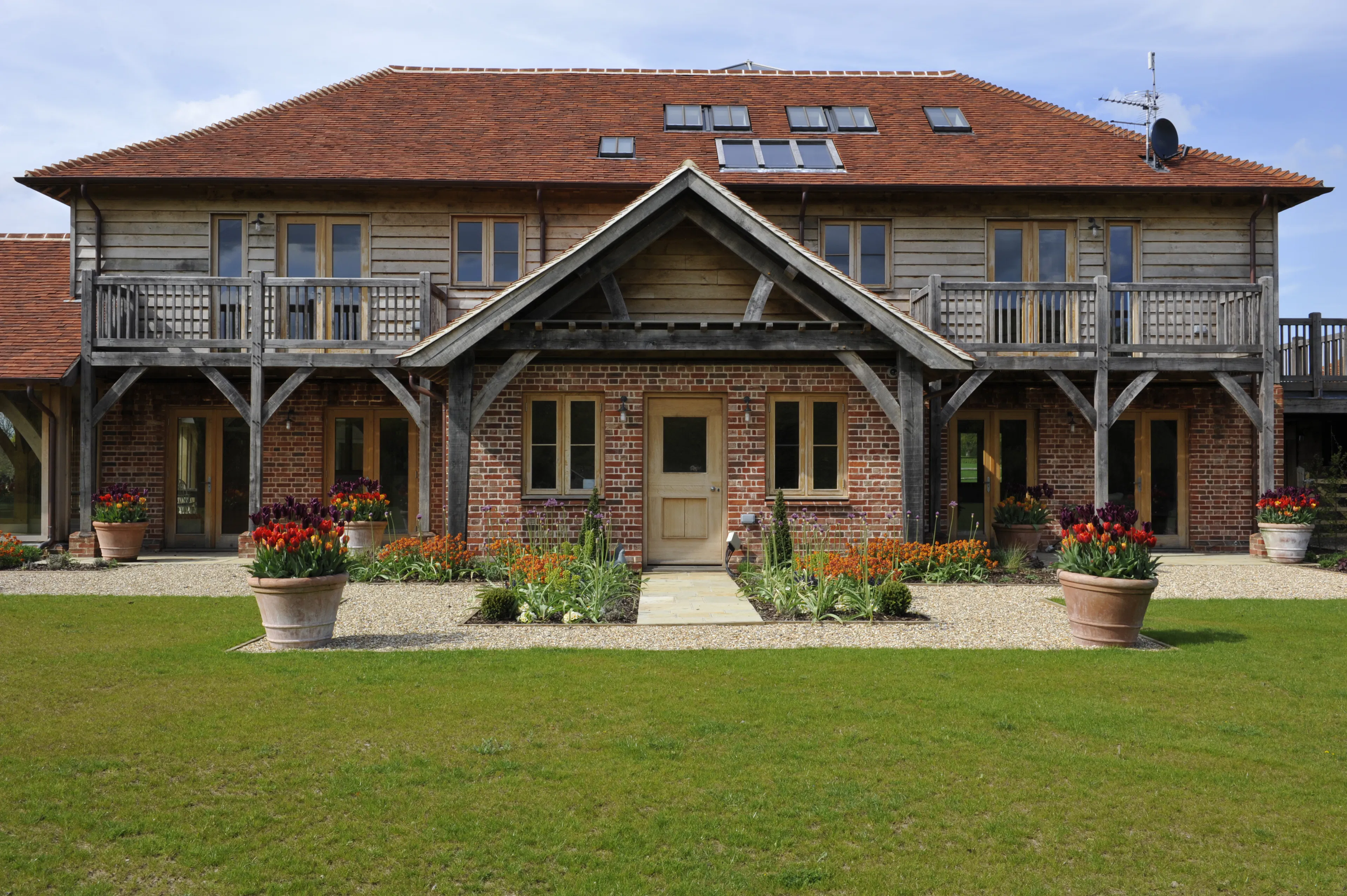 Exterior view of an expansive oak-framed family home with oak frame porch, balconies, and landscaped gardens