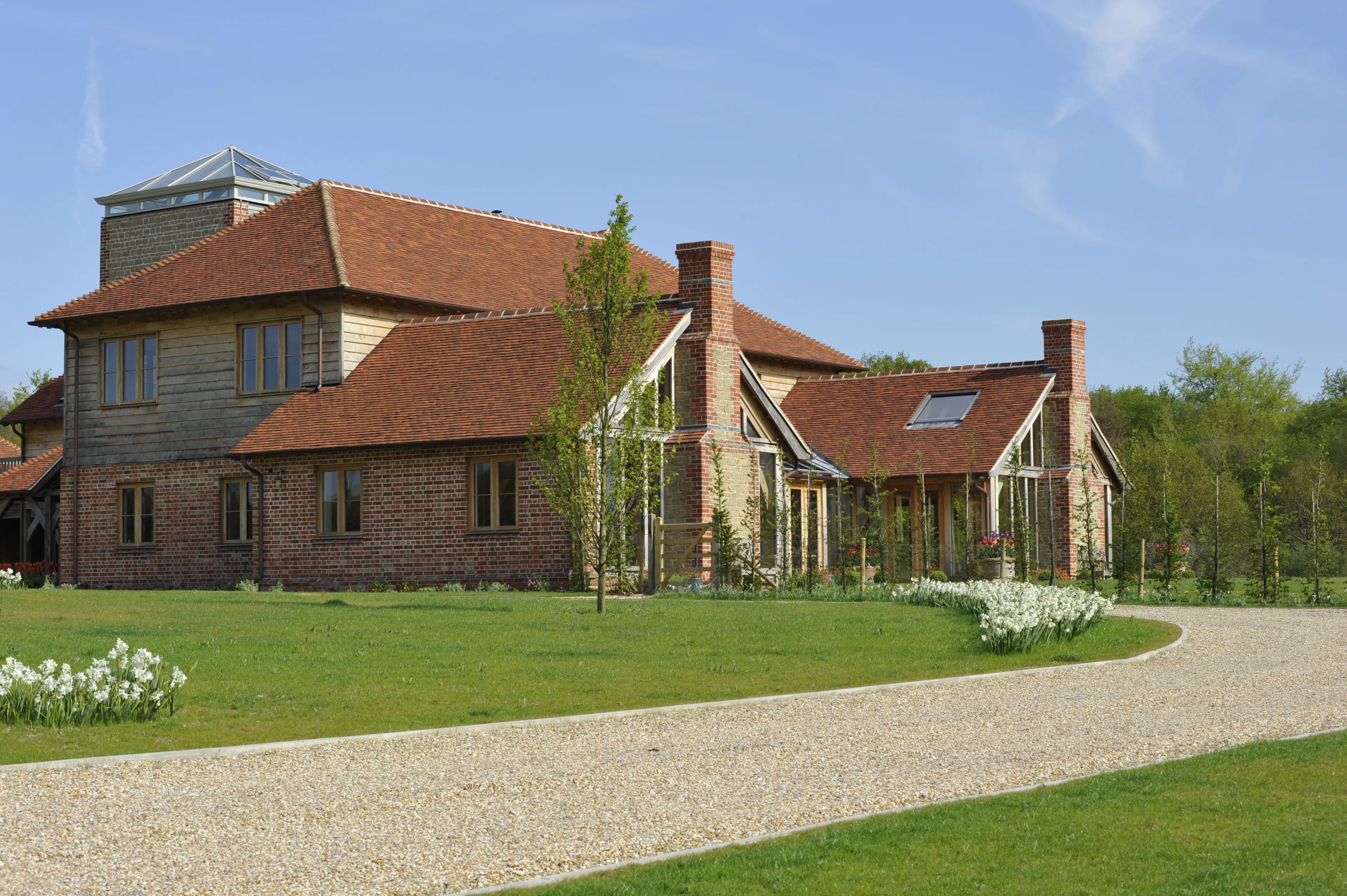 Exterior view of an expansive oak-framed family home with multiple levels and a unique central viewing tower
