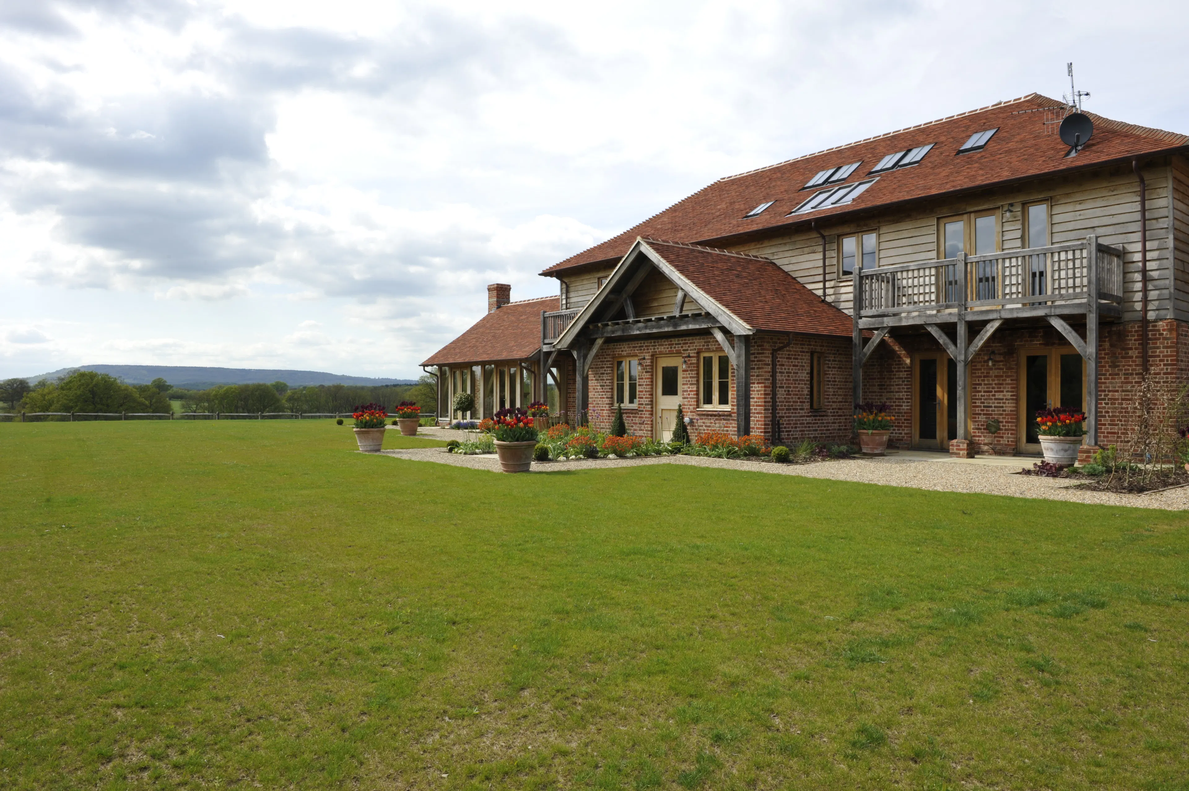 Exterior view of an expansive oak-framed family home with oak frame porch, balconies, and landscaped gardens