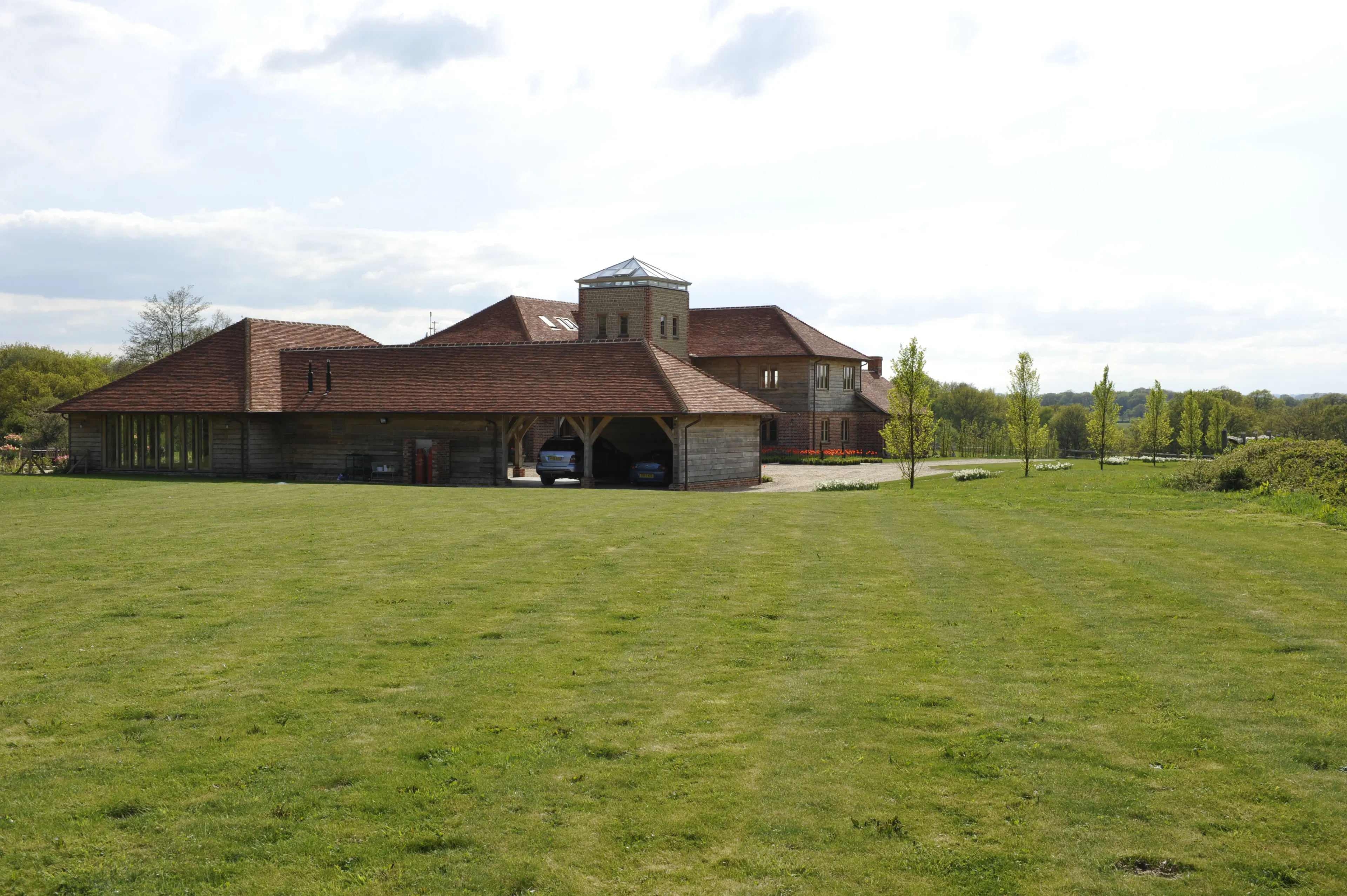 Exterior view of an expansive oak-framed family home with multiple levels and a unique central viewing tower