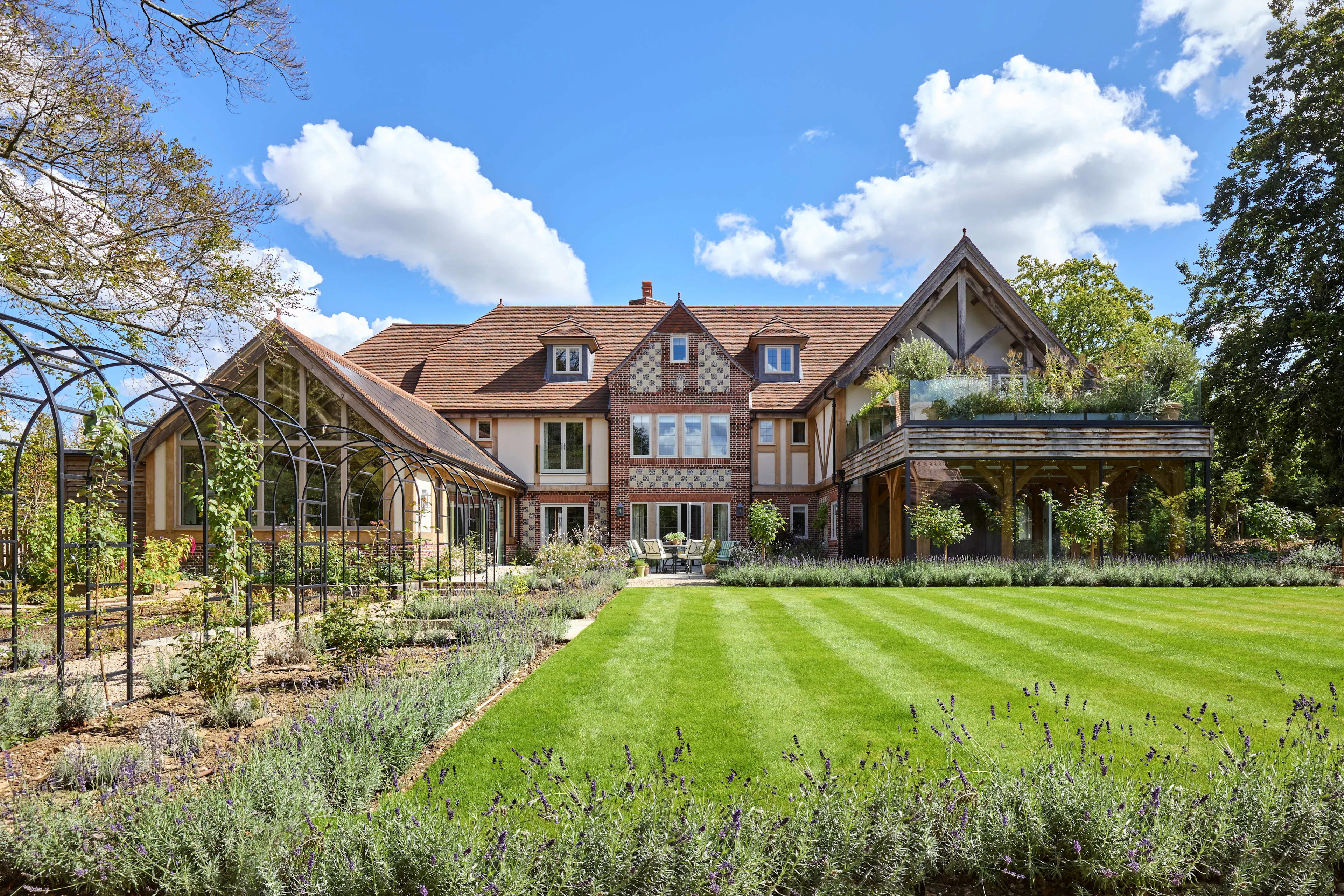 The rear of a large 6 bedroom oak framed home with a glazed swimming pool room and large green lawn