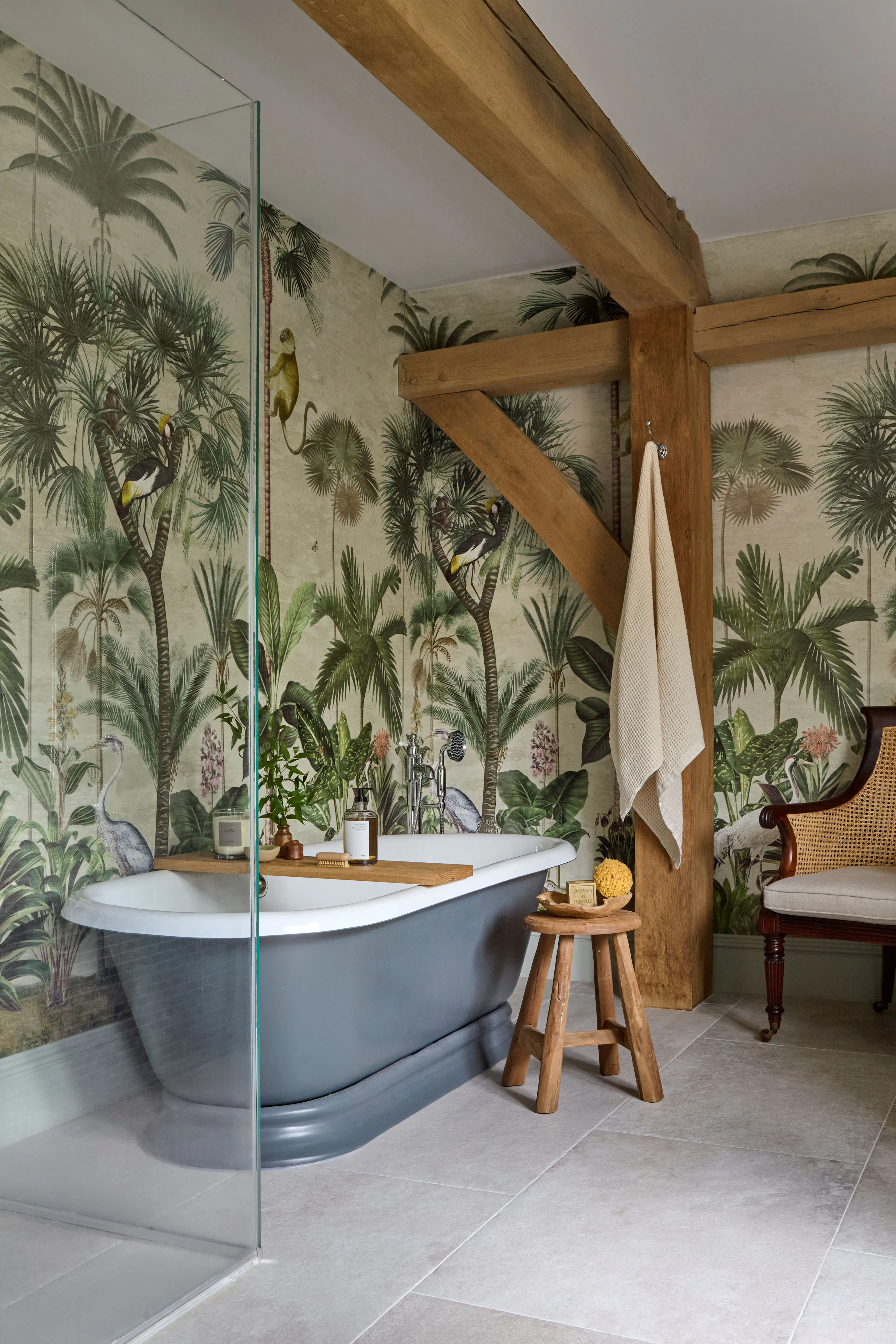 A bathroom with foliage wall paper and a grey freestanding bath in a large 6 bedroom oak framed home