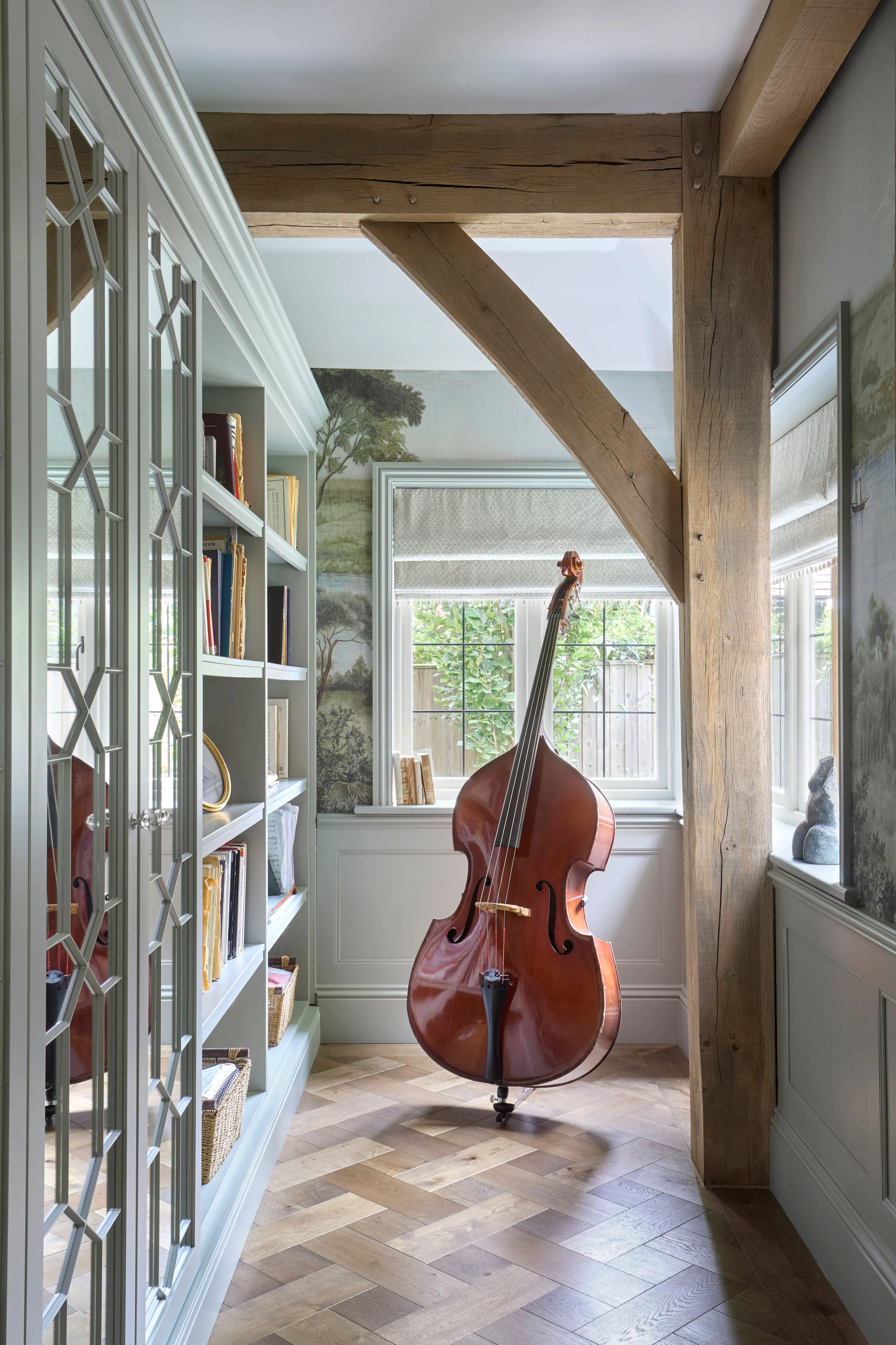 A music room with a cello and built in bookshelves of a large 6 bedroom oak framed home