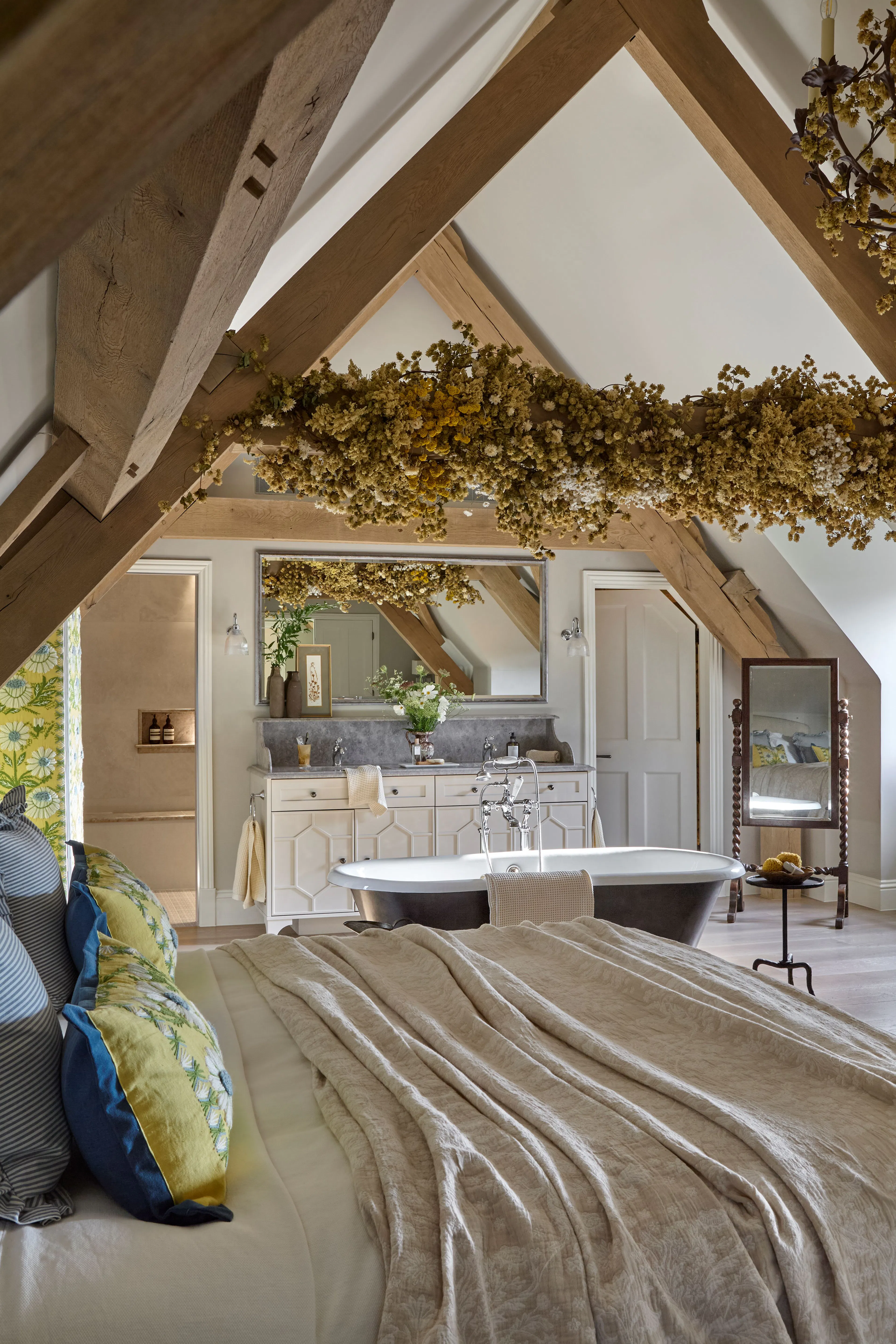 A vaulted ceiling bedroom with a freestanding bath in the loft space of a large 6 bedroom oak framed home