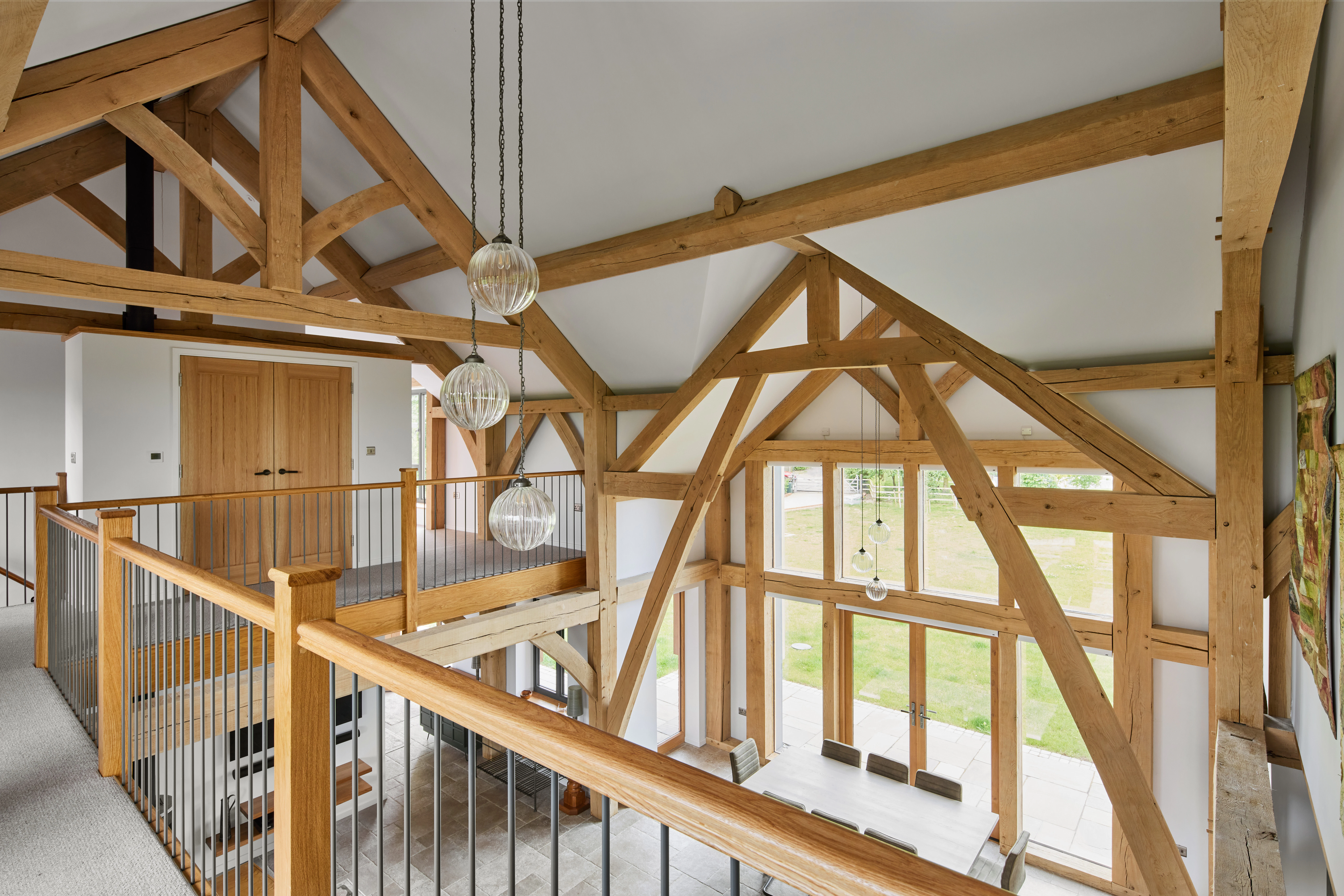 A large open plan living, dining and kitchen space with vaulted ceilings and a mezzanine landing area in a large oak framed home