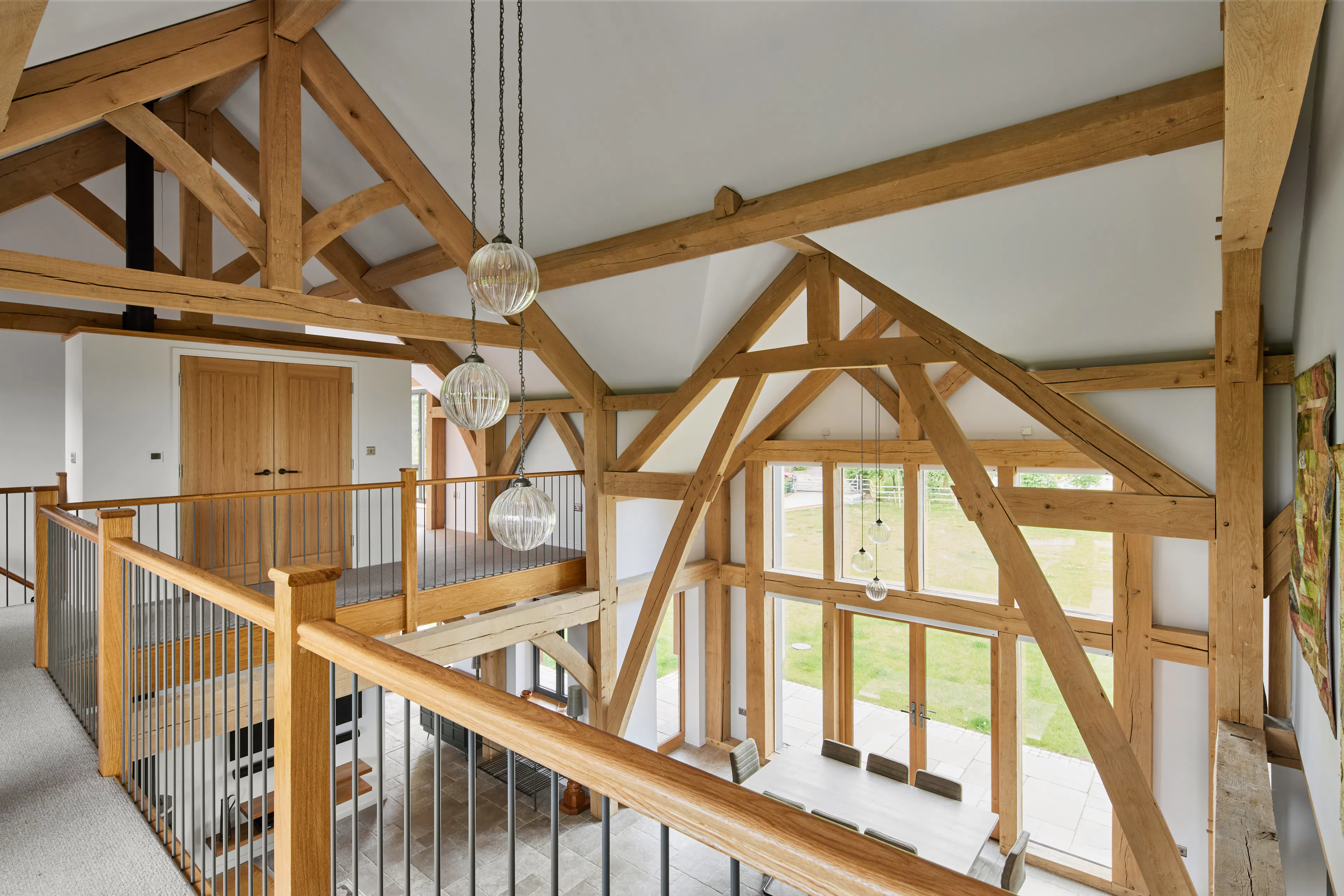A large open plan living, dining and kitchen space with vaulted ceilings and a mezzanine landing area in a large oak framed home
