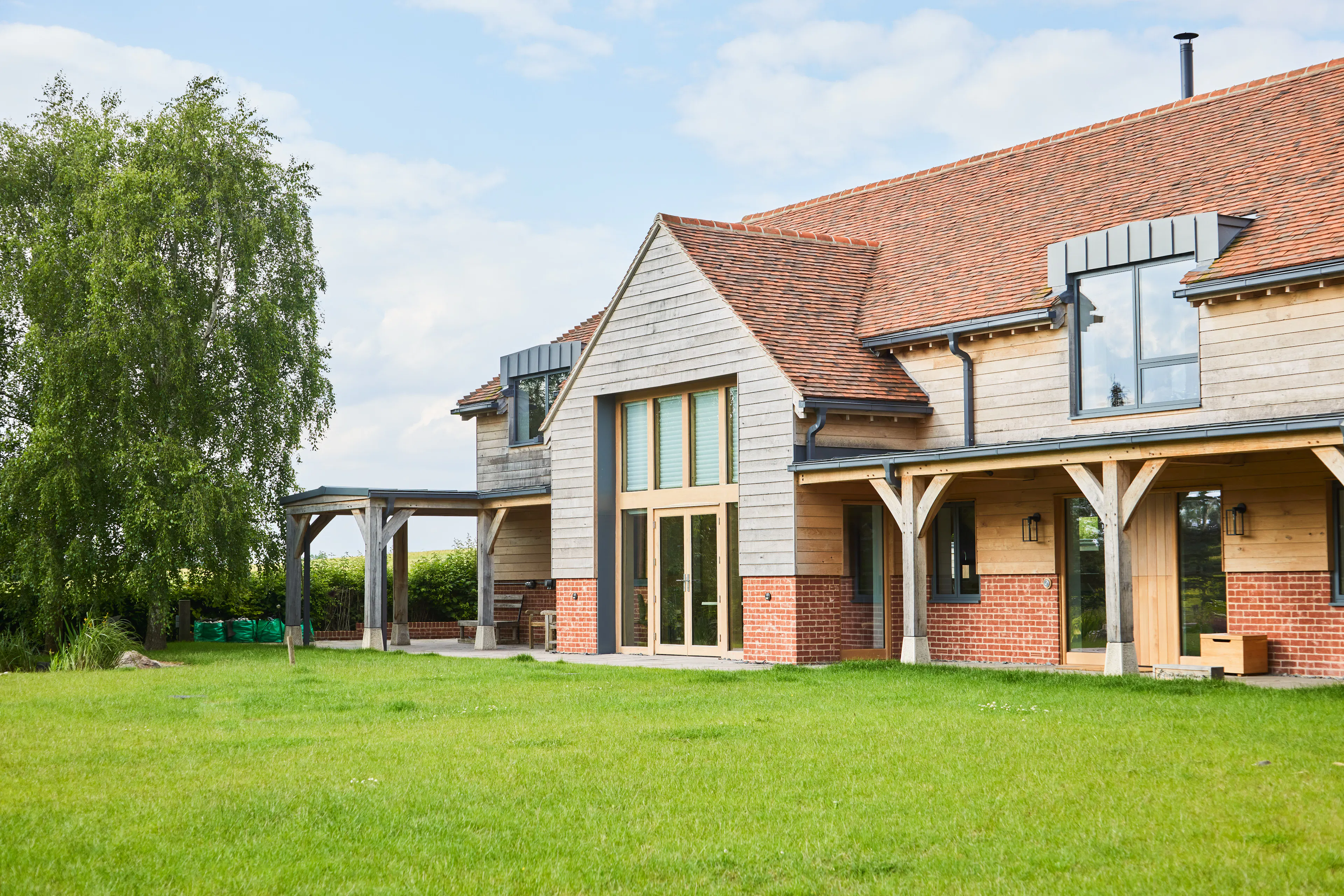 A green lawn in front of a large oak framed home with an oak framed veranda