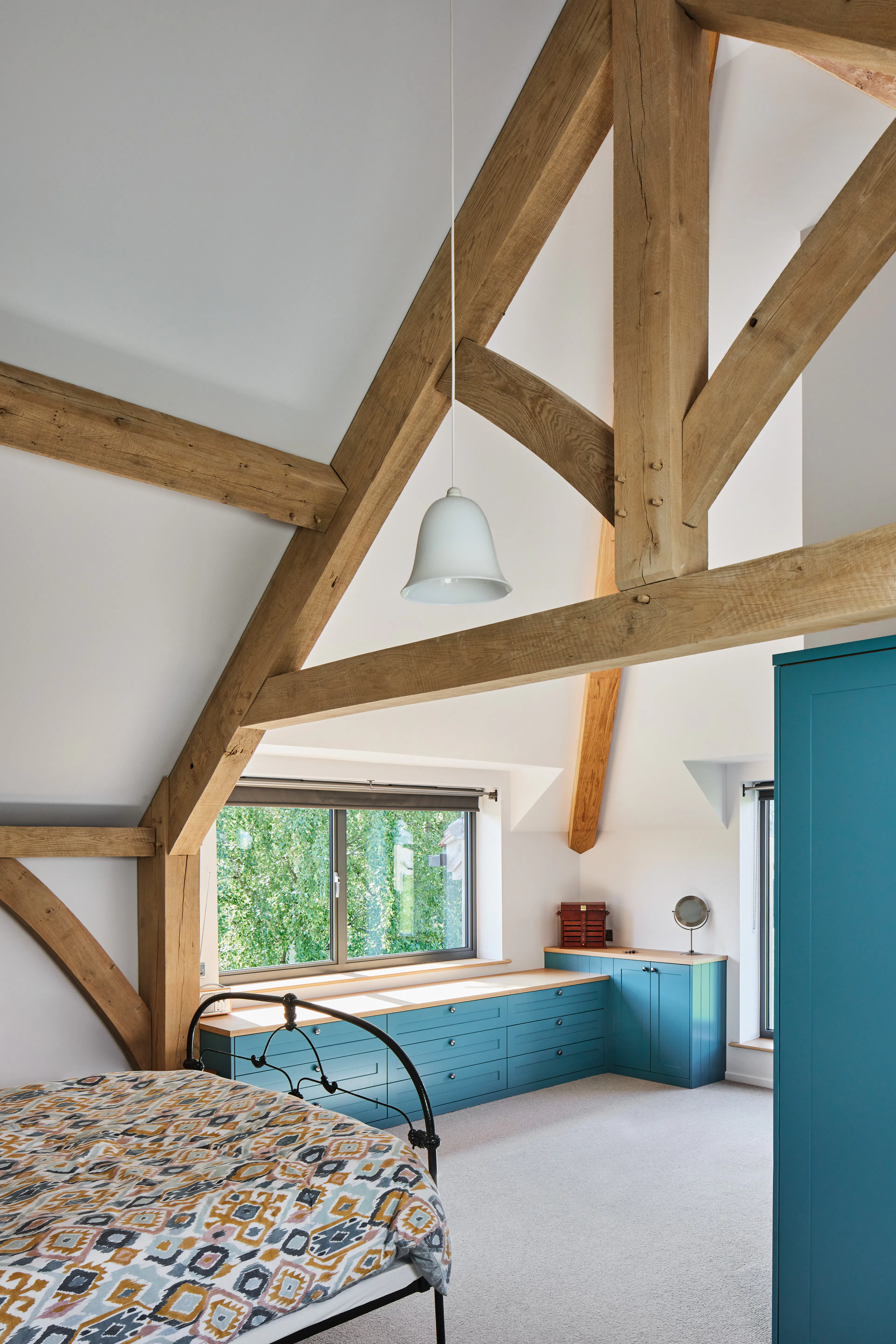 A bedroom with a vaulted ceiling in a large oak framed home