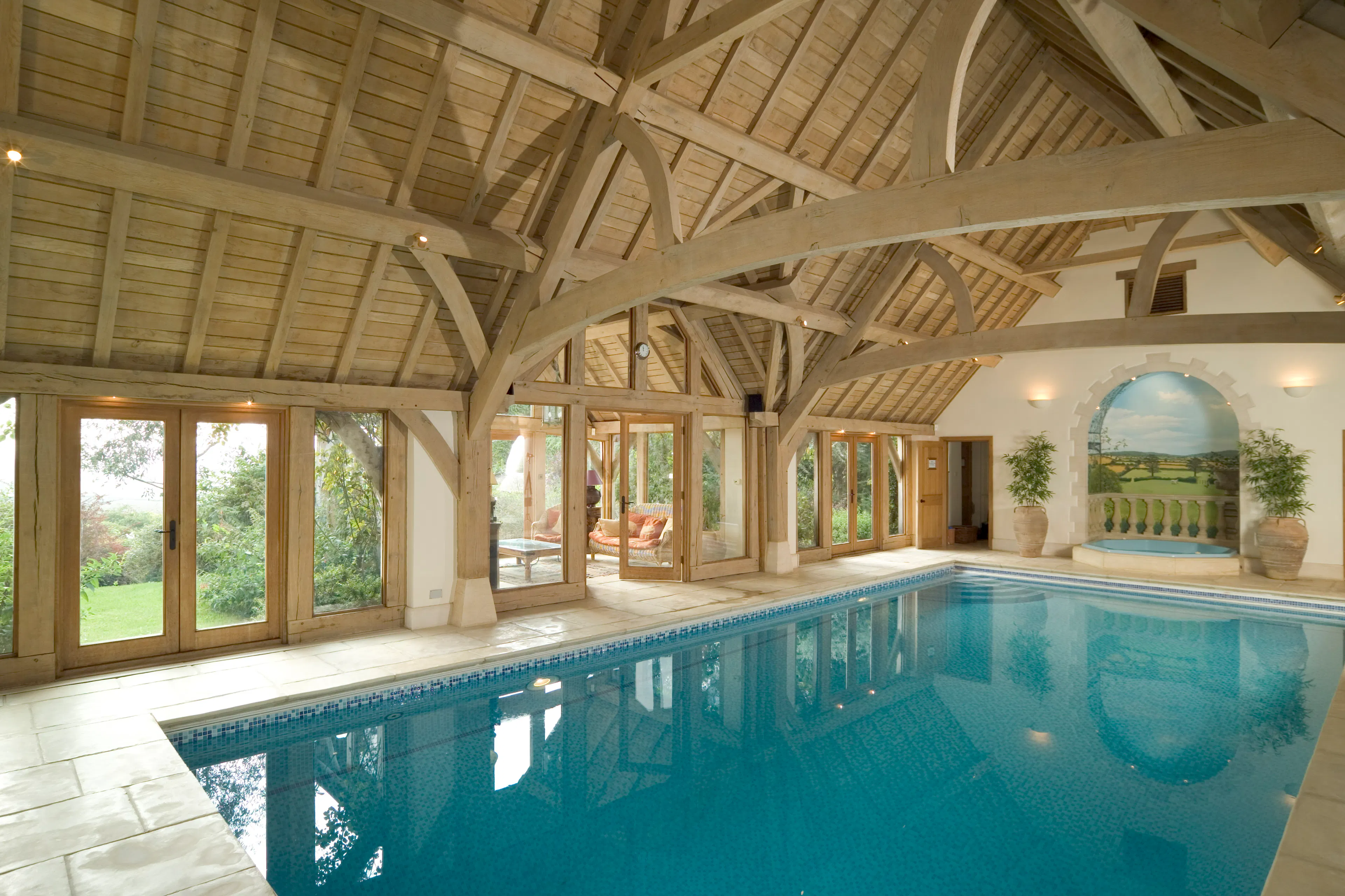 An oak framed swimming pool with sun coming through glazed windows