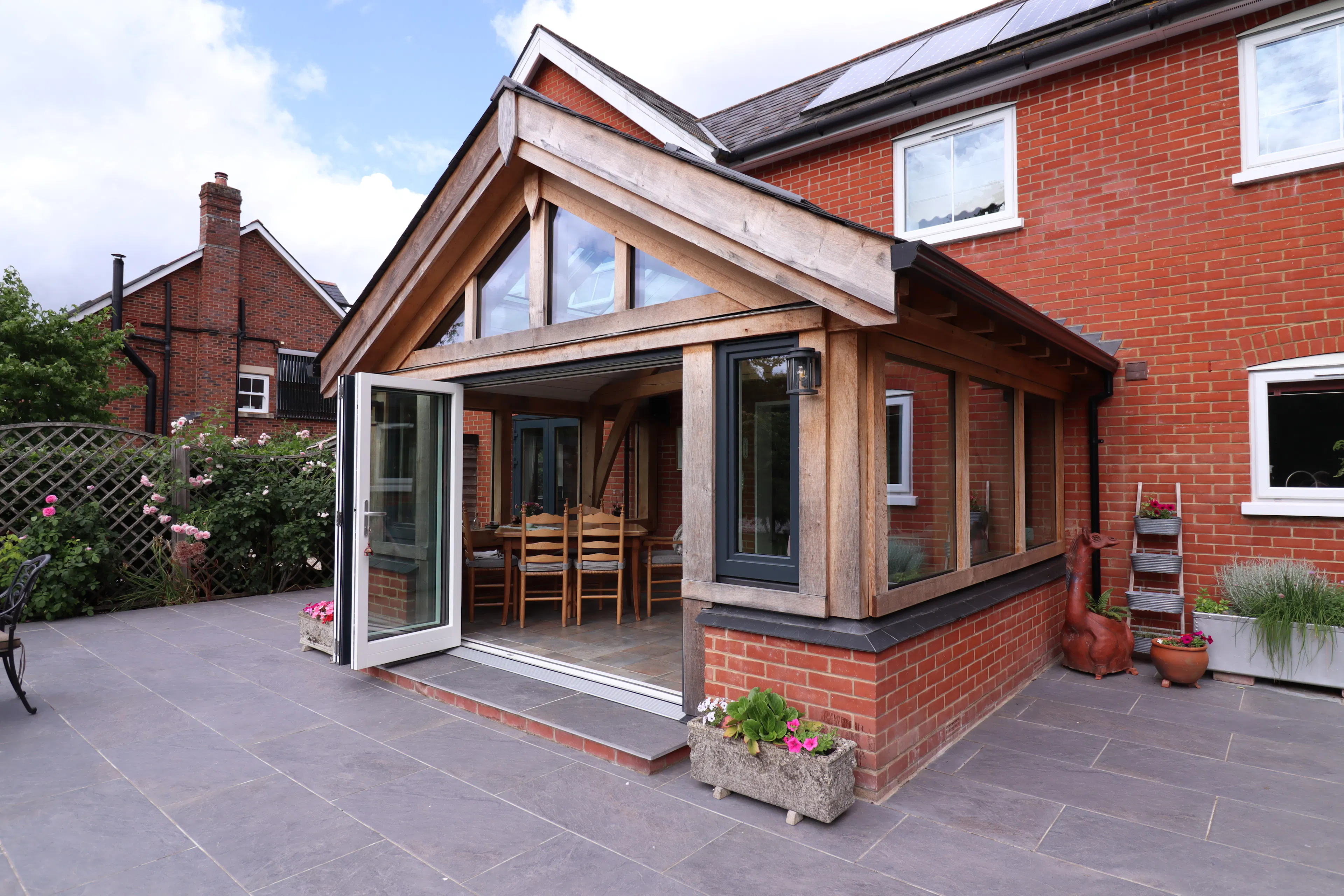 Exterior photo of an oak framed garden room with sliding doors opened