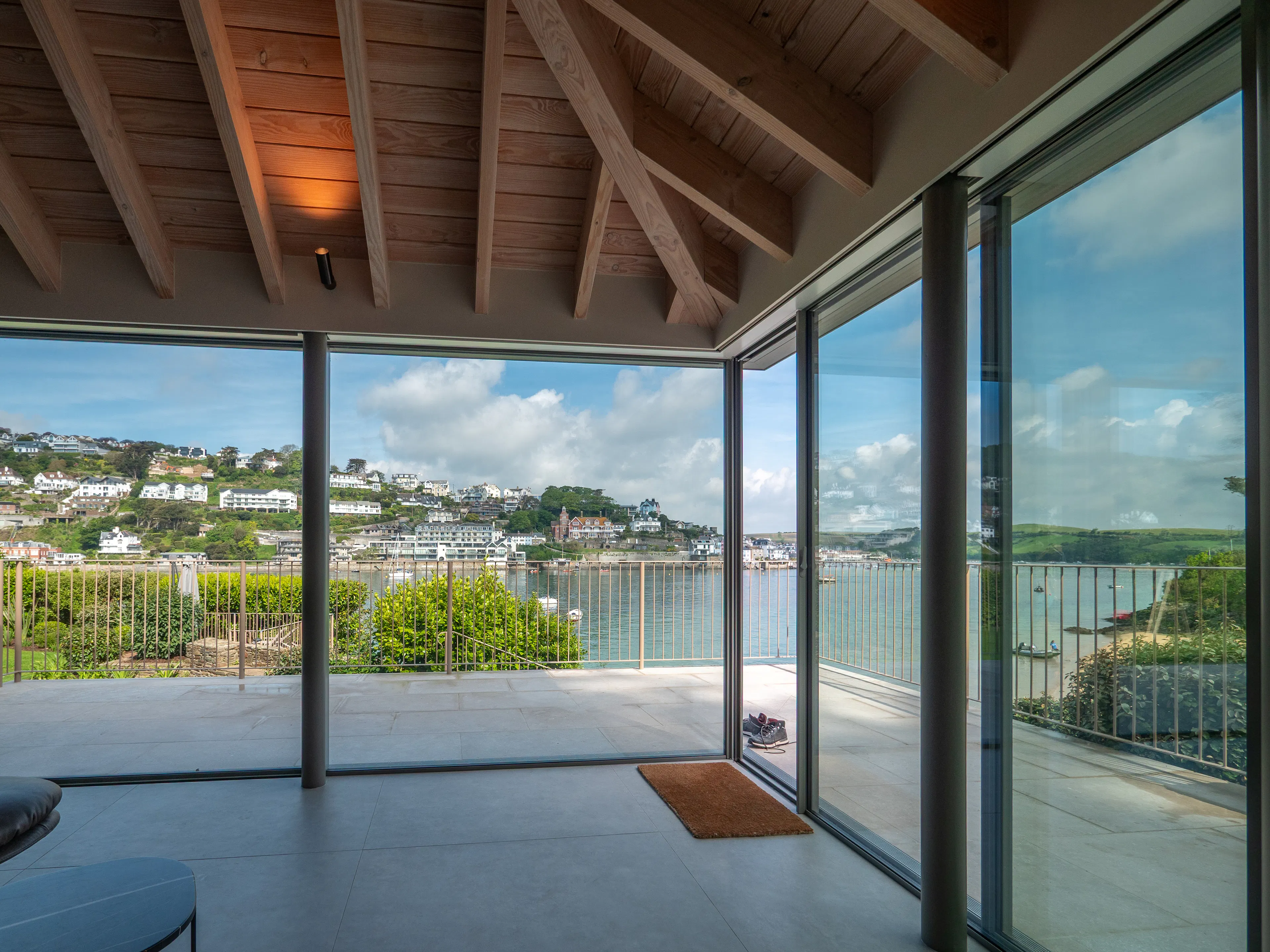 Glazed sliding doors with views of an estuary in a contemporary Douglas fir glulam framed kitchen extension