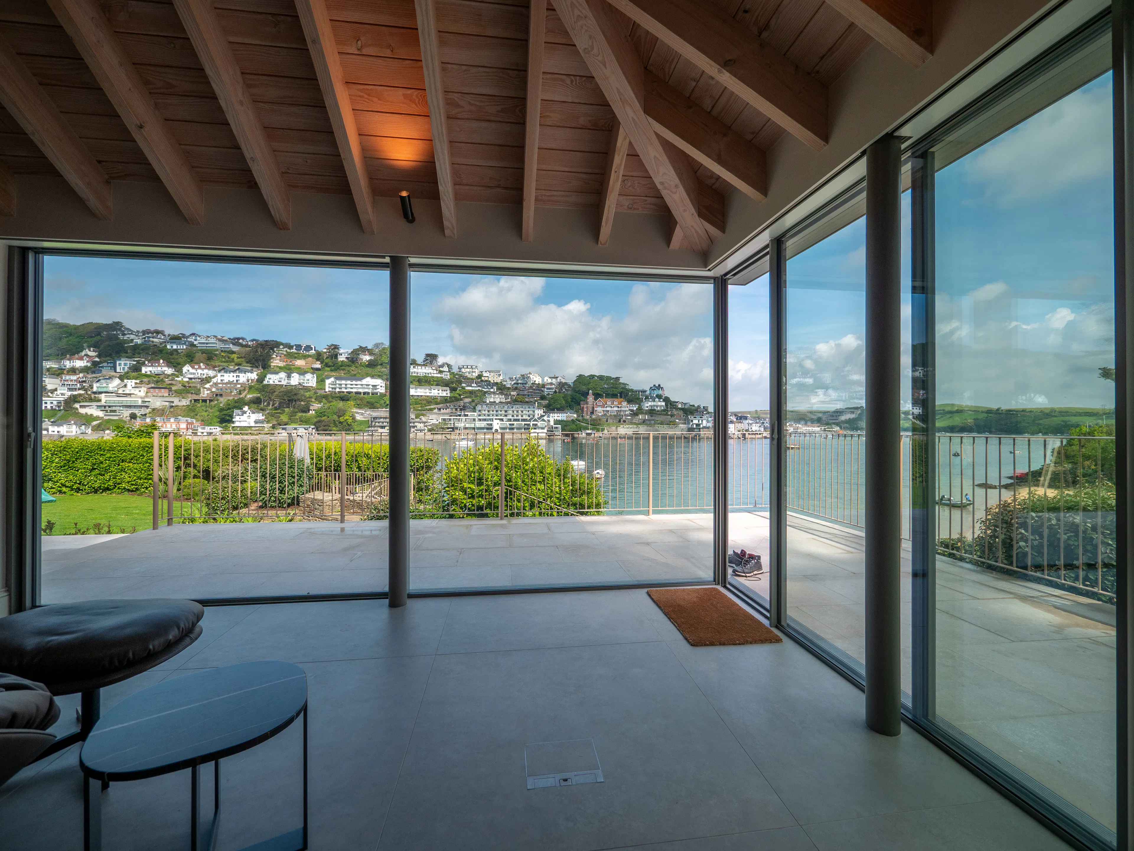 Glazed sliding doors with views of an estuary in a contemporary Douglas fir glulam framed kitchen extension