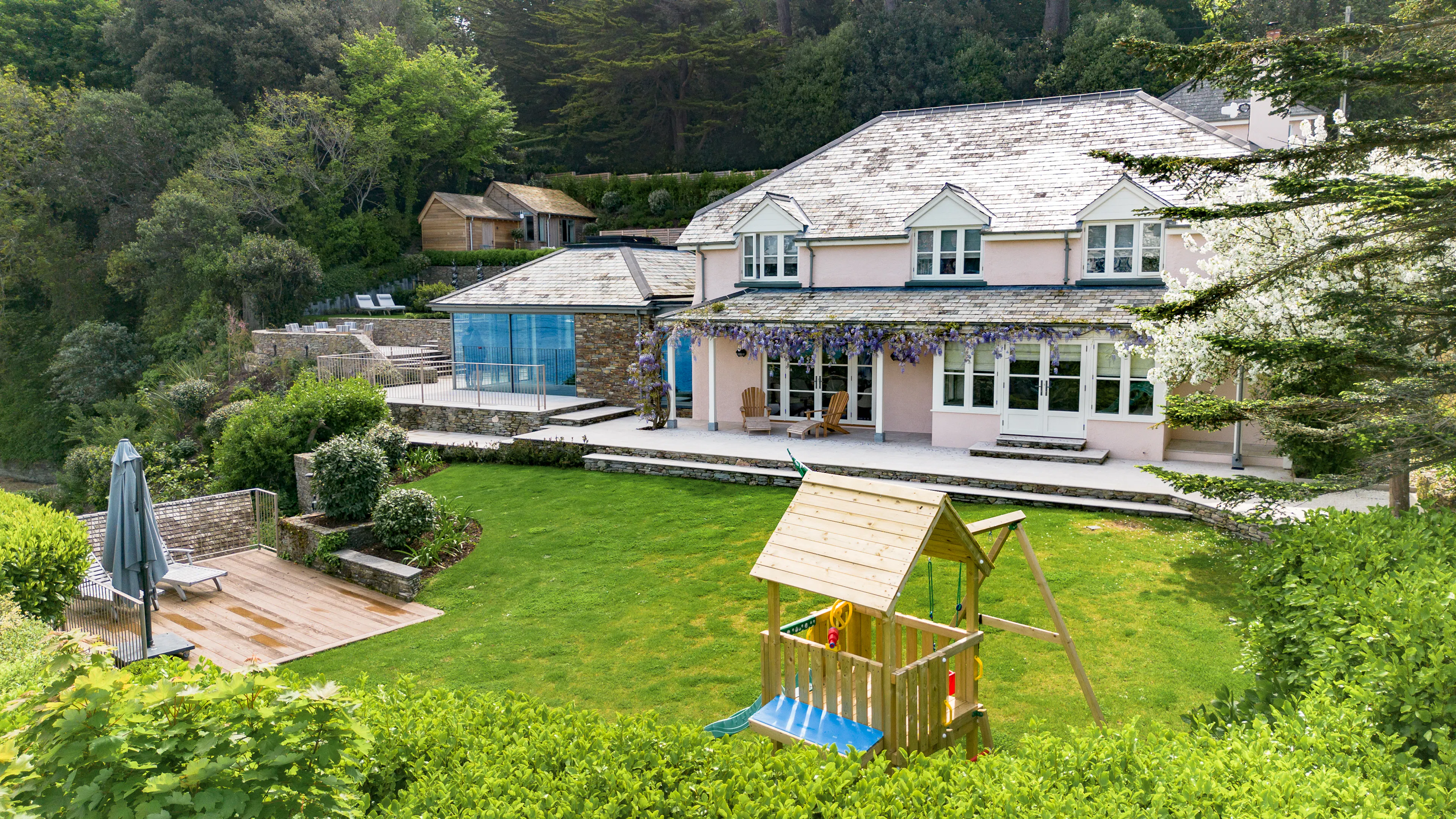 A contemporary Douglas fir glulam framed kitchen extension to a stone cottage with a terraced garden and green lawn