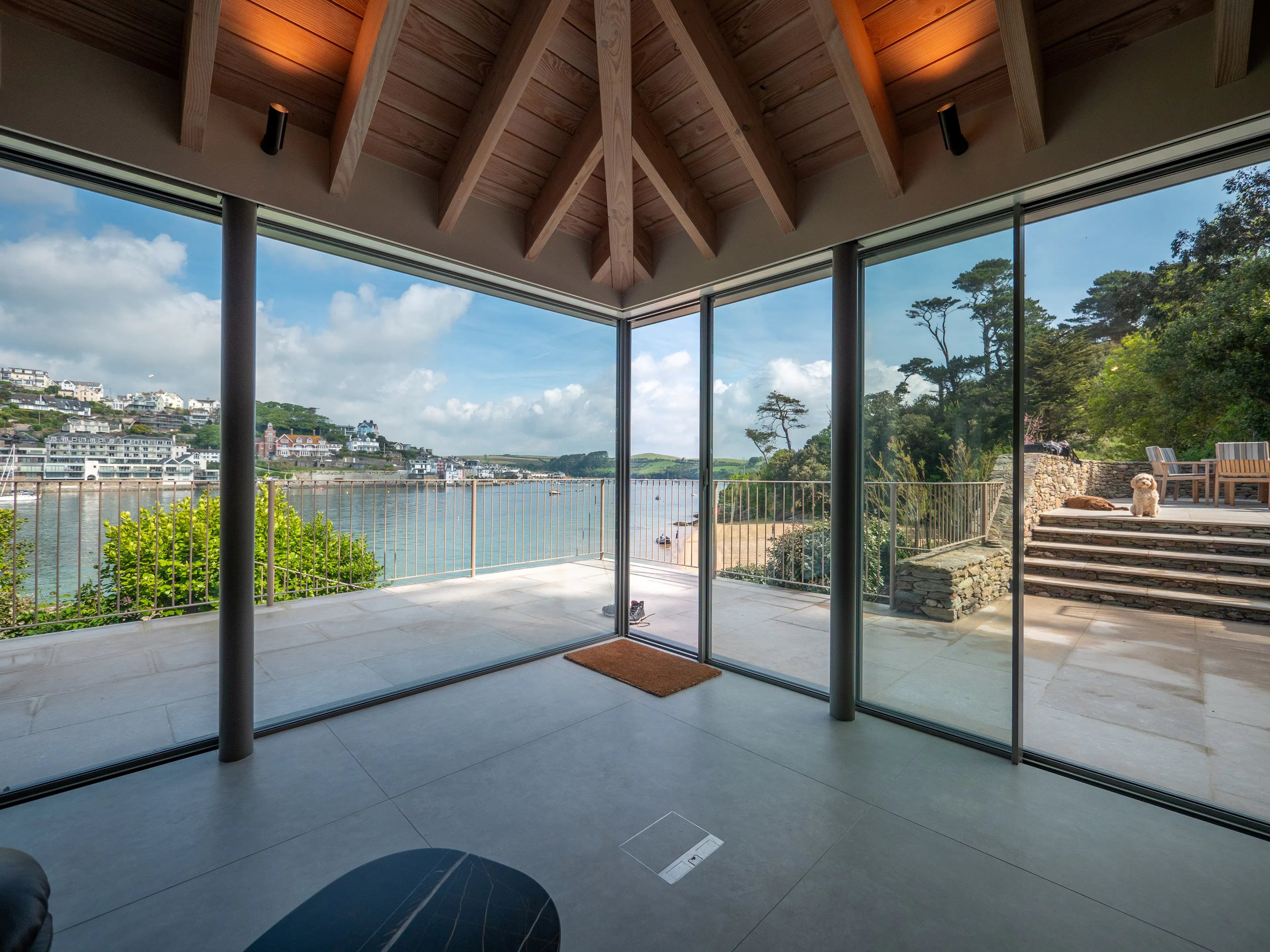 Glazed sliding doors with views of an estuary in a contemporary Douglas fir glulam framed kitchen extension