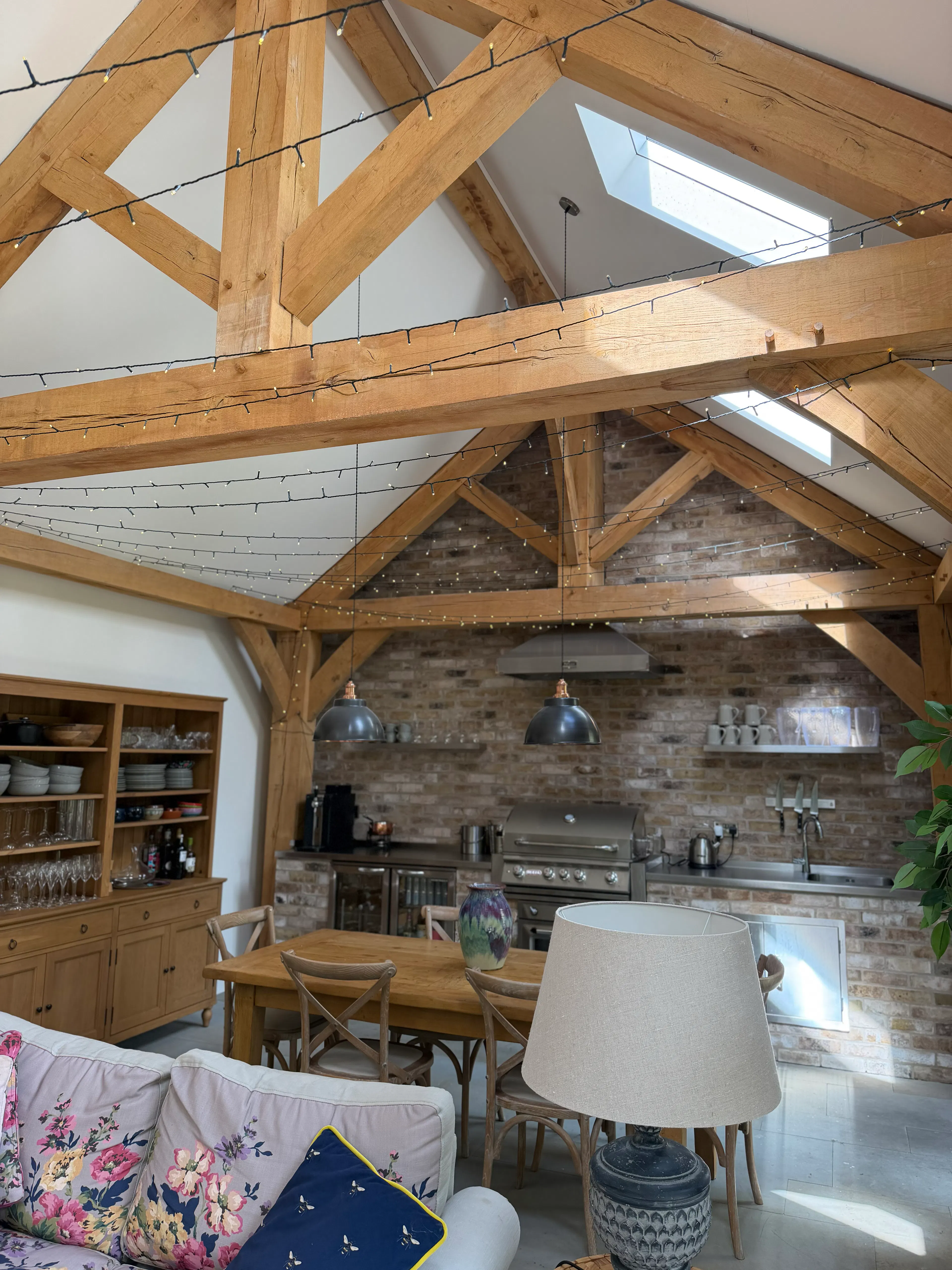 Open-plan garden room interior with exposed oak frame construction and a king post truss, creating a bright and spacious living area