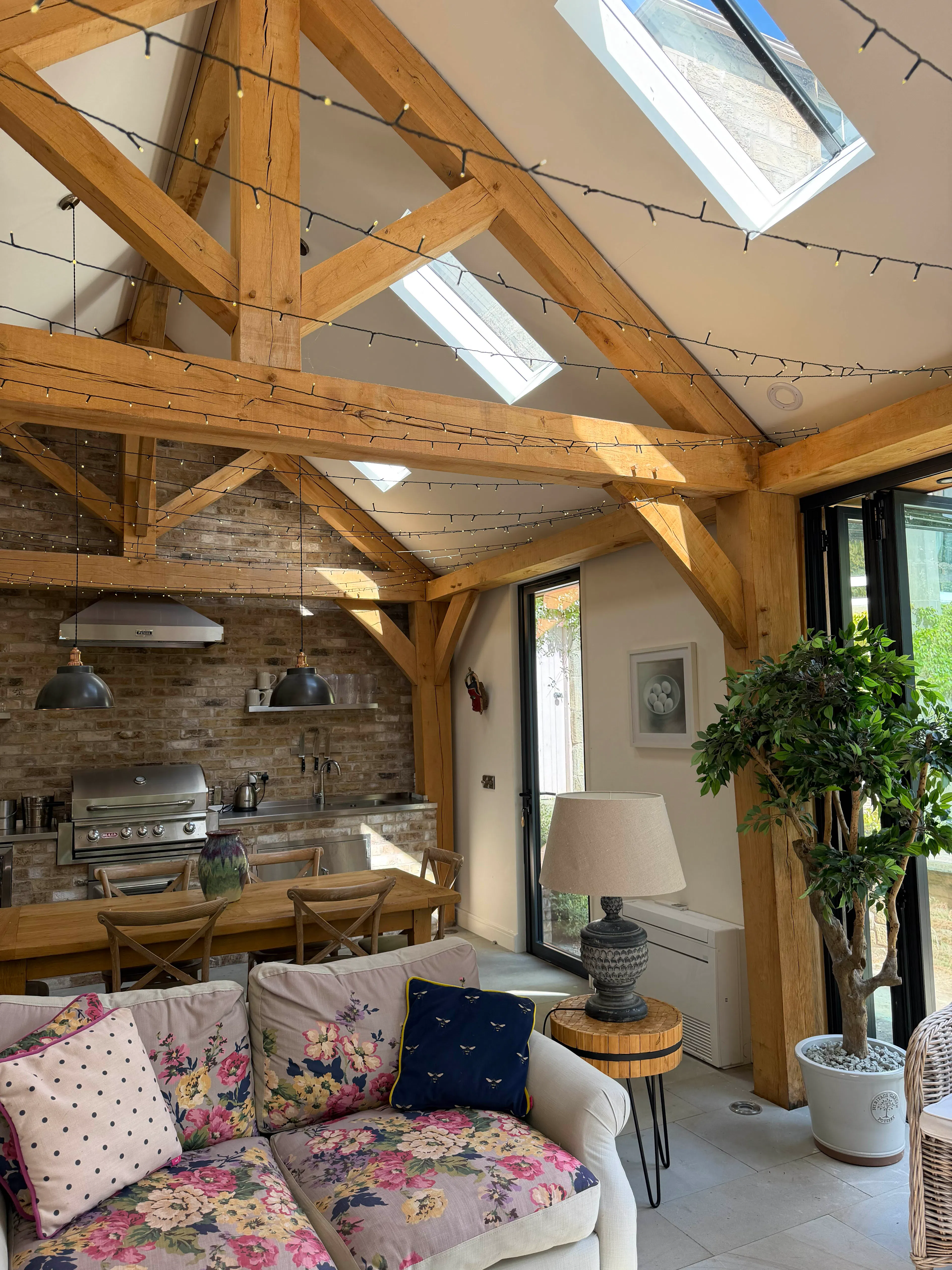 Garden room interior with exposed oak frame construction, featuring a king post truss, structural oak post, and a vaulted ceiling that enhances the sense of space
