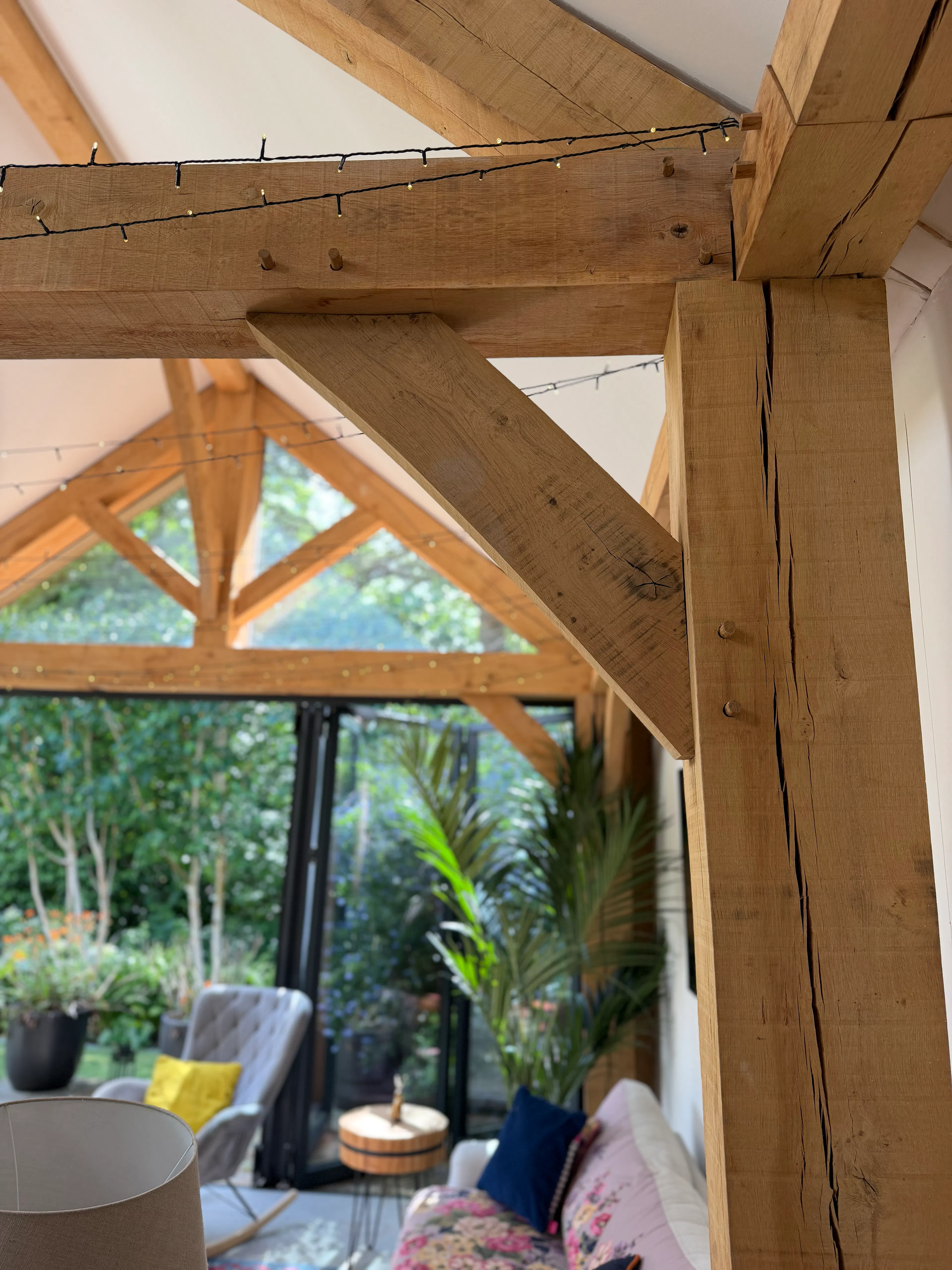 Garden room interior with exposed oak frame construction, featuring a king post truss, structural oak post, and extensive glazing bringing natural light into the space