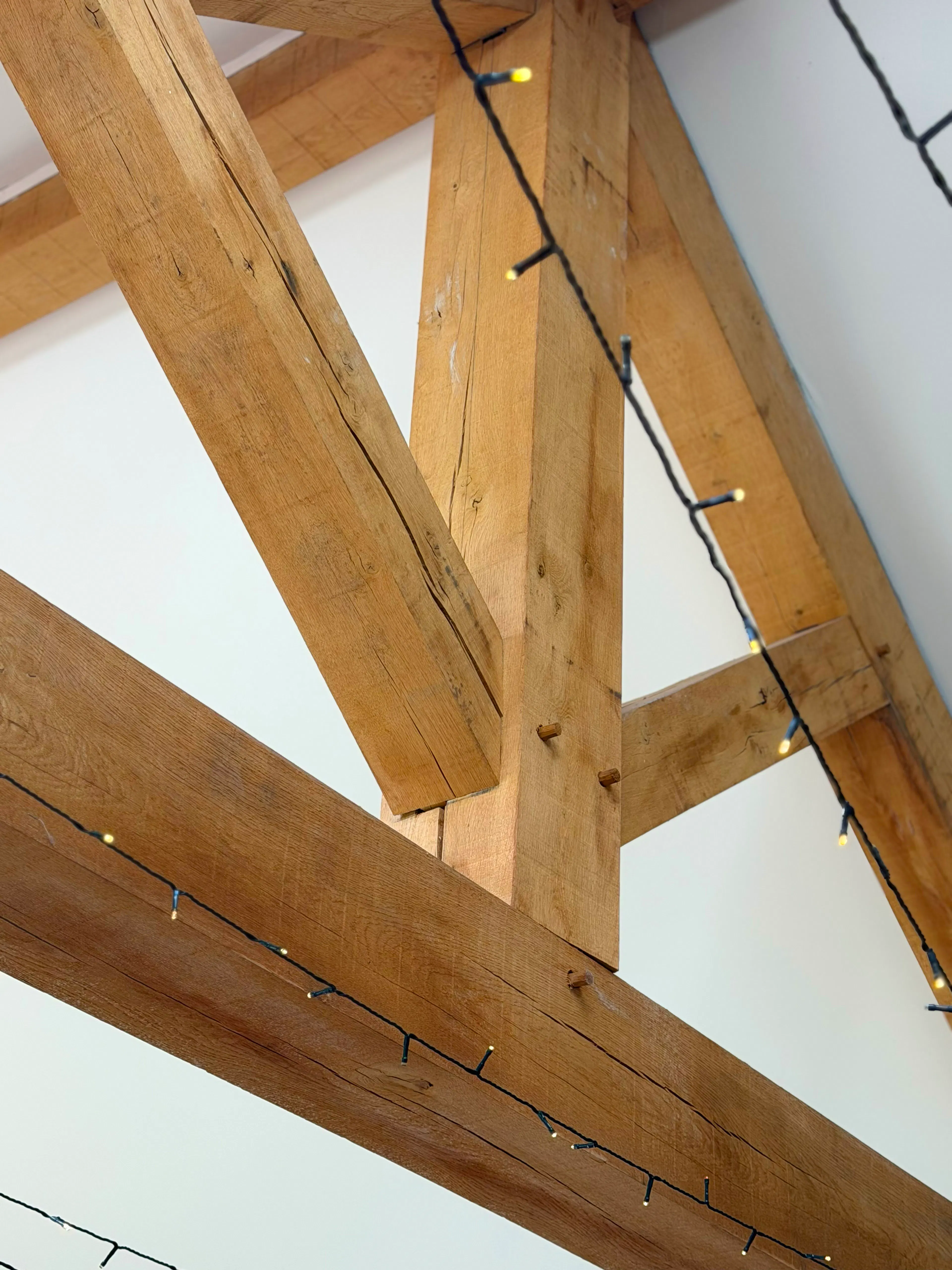 Interior garden room with exposed oak frame construction and a king post truss, showing structural timber connections and joint detailing