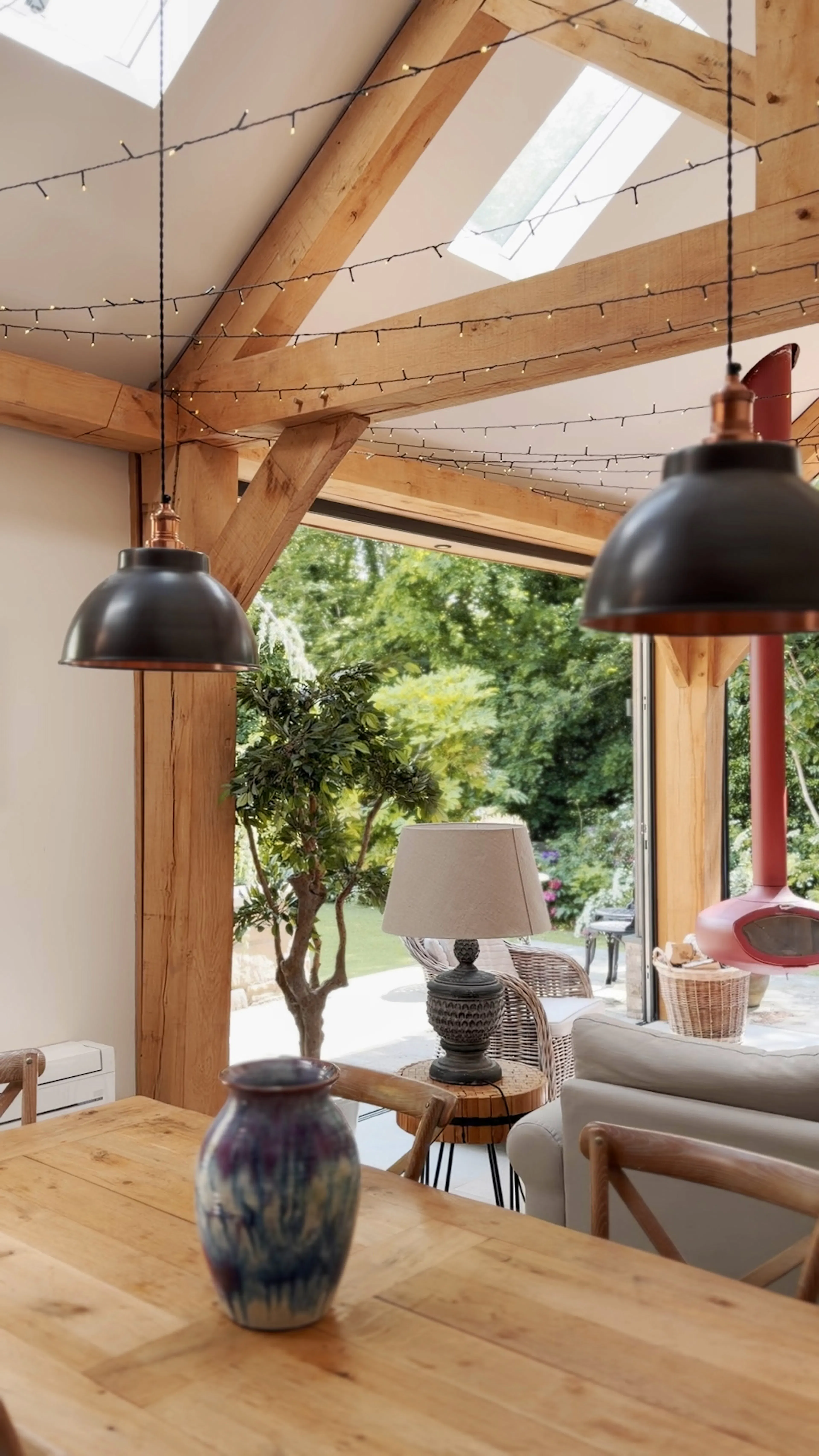 Open-plan garden room interior with exposed oak frame construction and a king post truss, forming a bright and spacious living area
