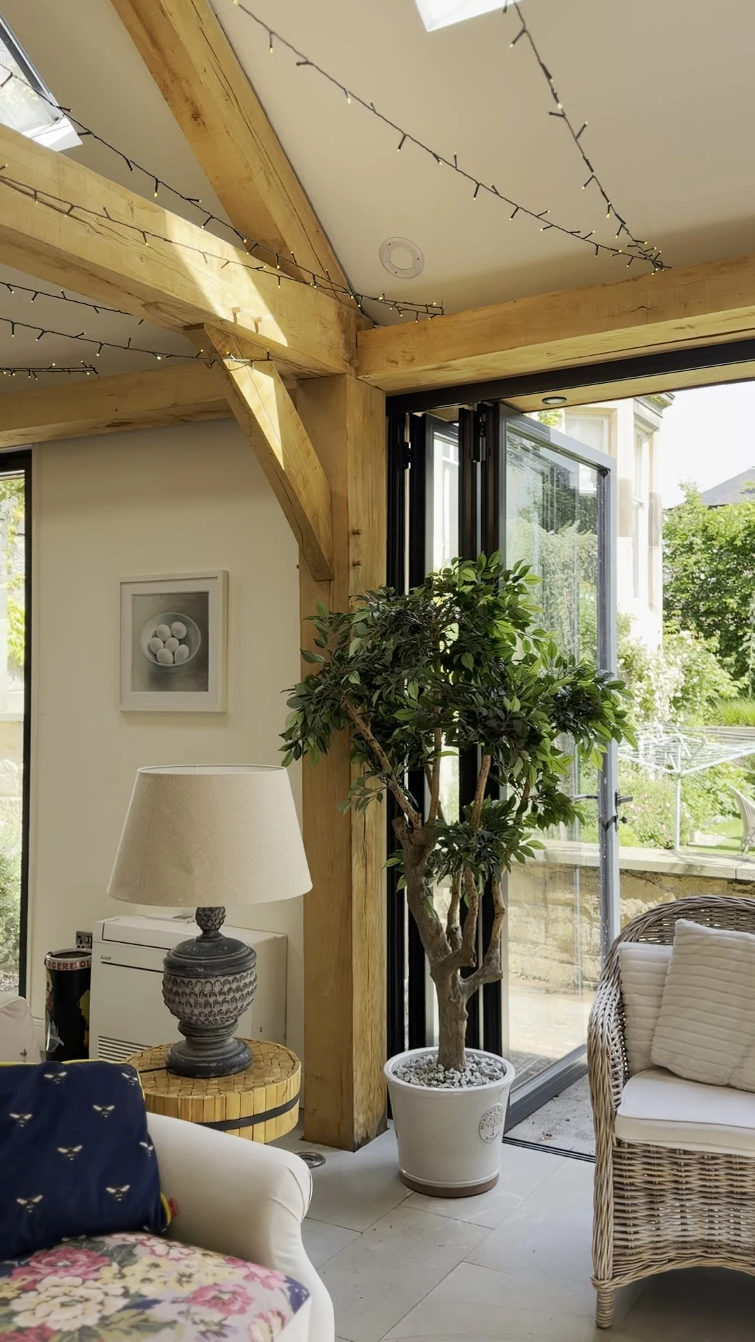Interior garden room with exposed oak frame construction, featuring a corner post and decorative indoor plants within a bright living space
