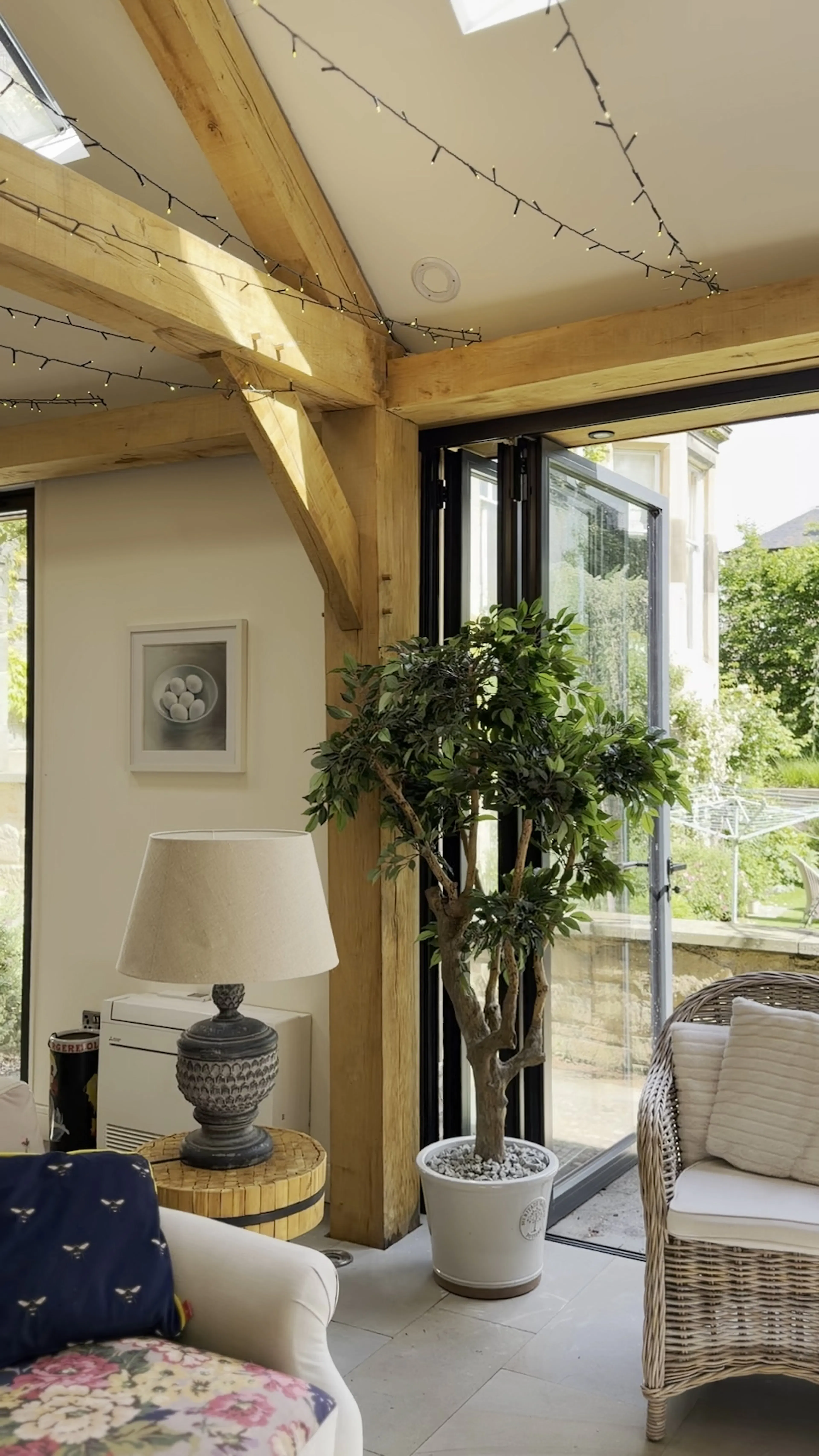 Interior garden room with exposed oak frame construction, featuring a corner post and decorative indoor plants within a bright living space