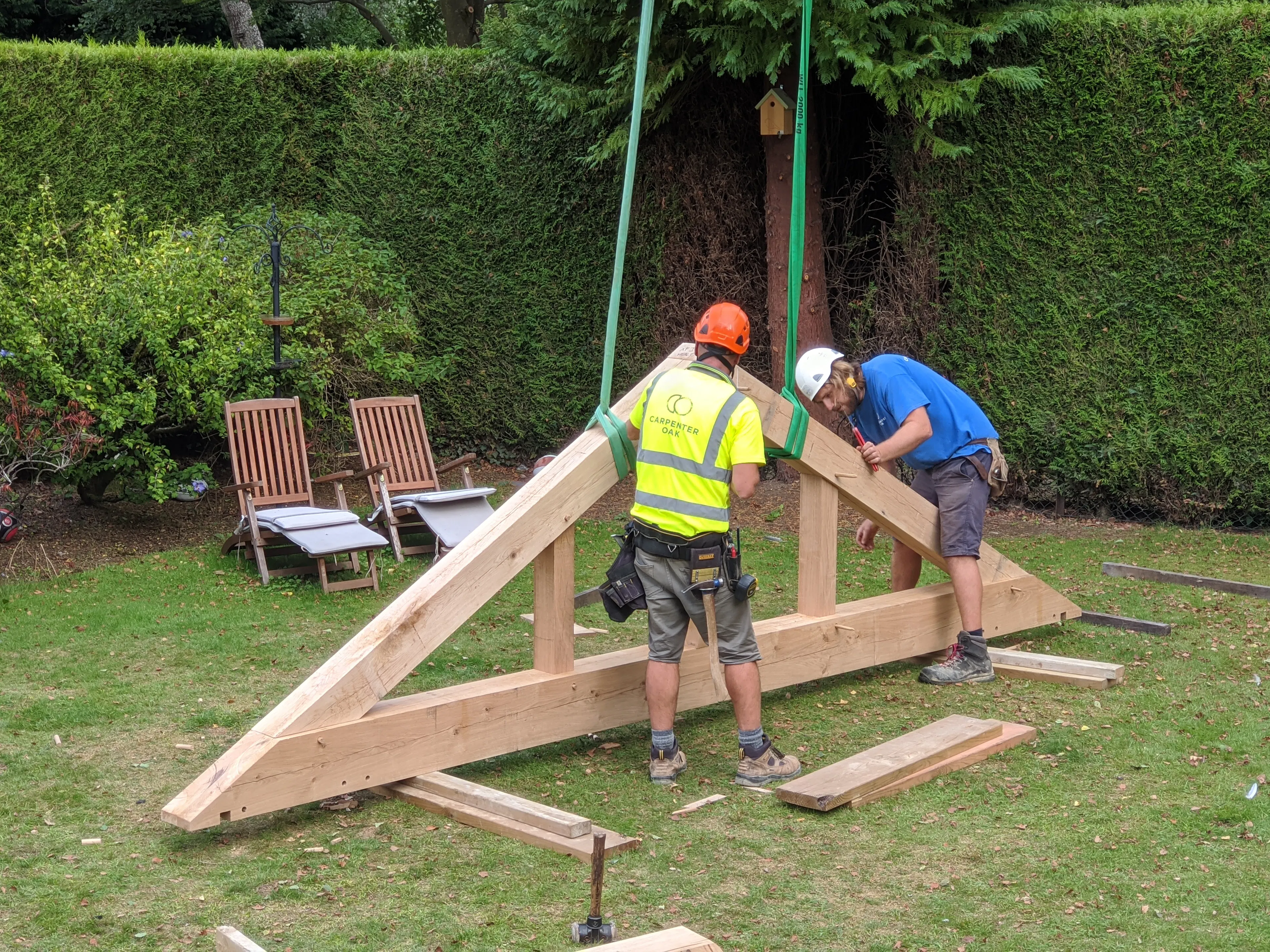Two carpenters getting a truss ready for a crane to lift it into place, during the installation of a frame for a modern oak framed extension